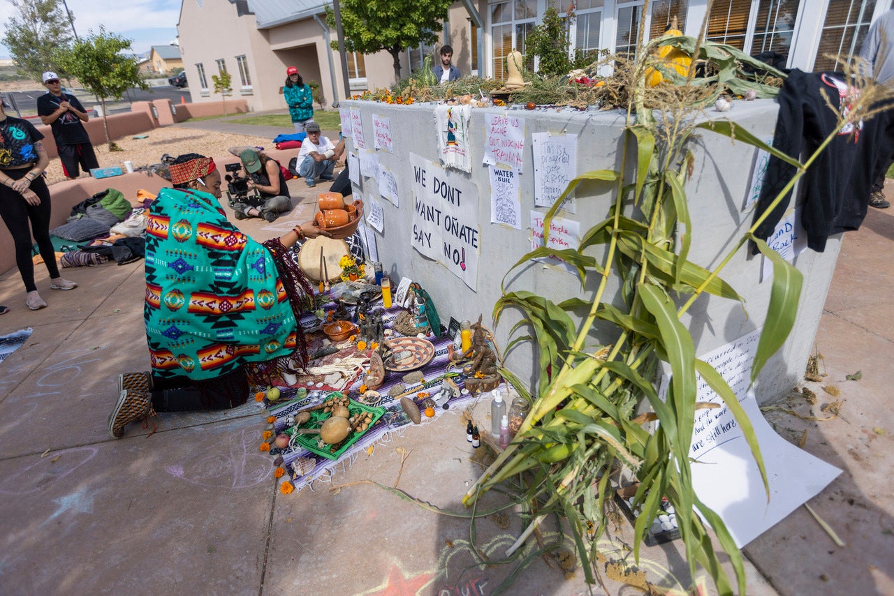 Activists place offerings at an empty pedestal where Rio Arriba County officials had planned to install a statue of Spanish conquistador