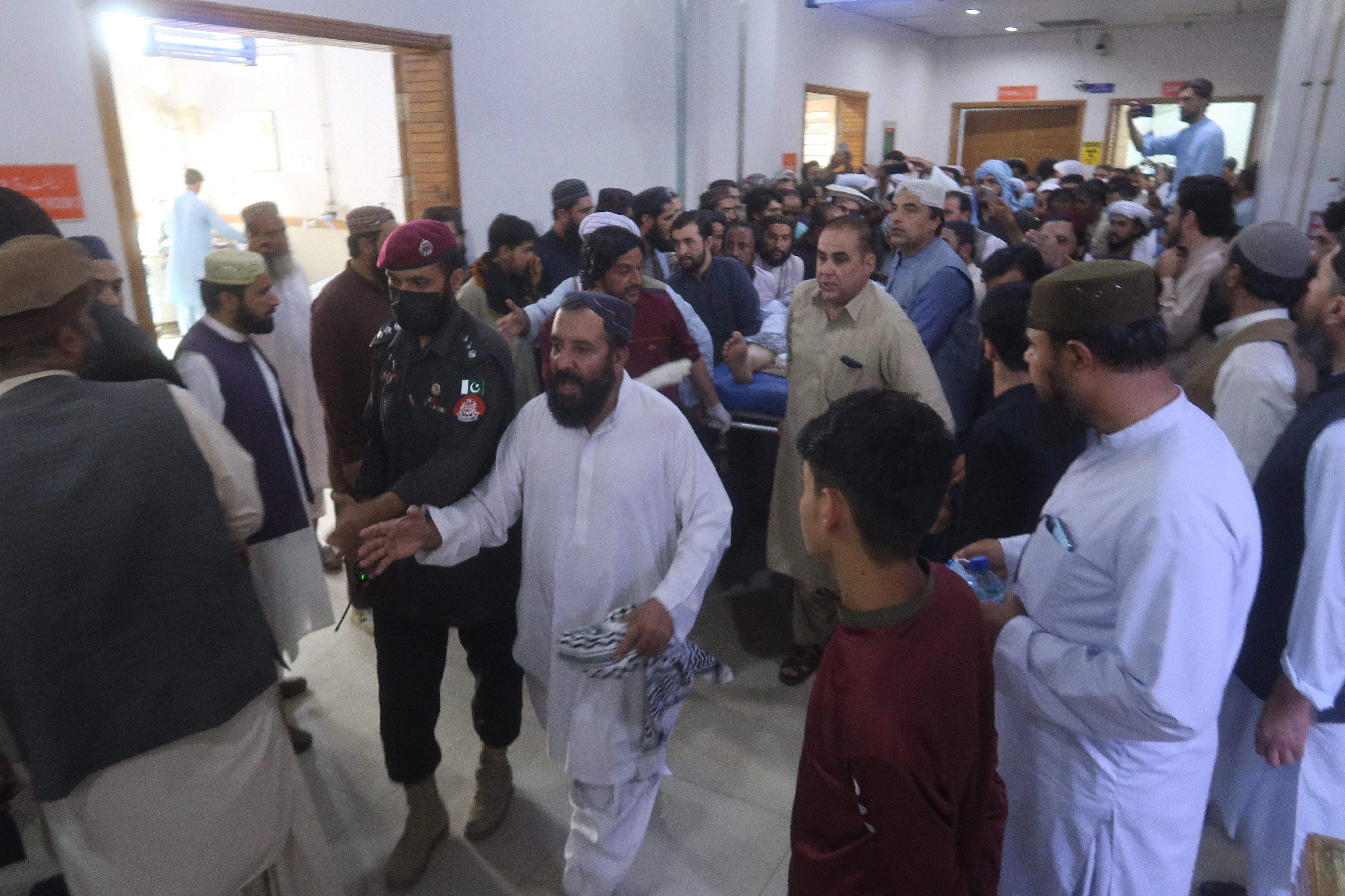 Police escort victims of the blast as they are moved at a hospital in Quetta