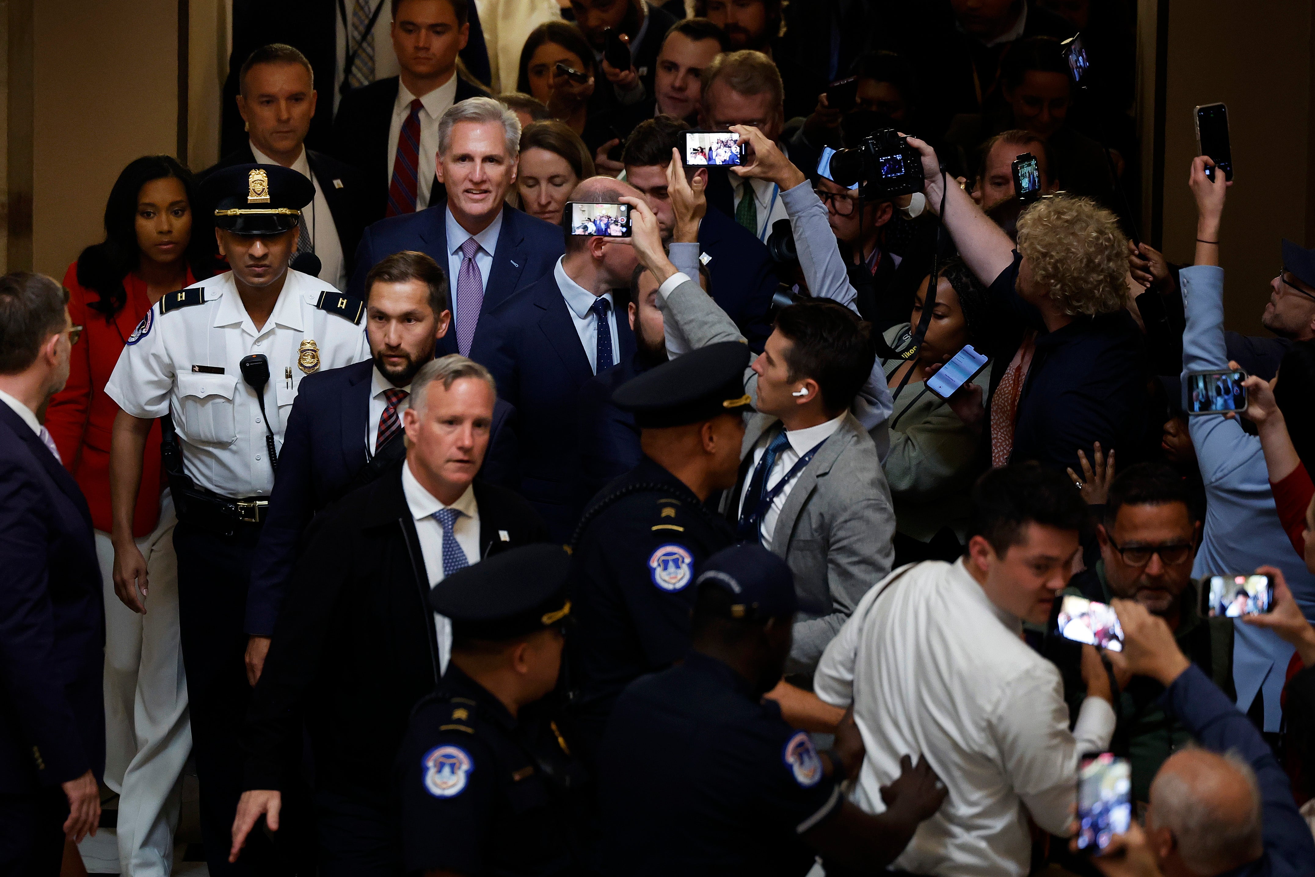 WASHINGTON, DC - OCTOBER 03: Former Speaker of the House Kevin McCarthy (R-CA) is surrounded by staff, security and journalists as he walks through Statuary Hall after he was ousted at the U.S. Capitol on October 03, 2023 in Washington, DC. McCarthy was removed by a motion to vacate, an effort led by a handful of conservative members of his own party, including Rep. Matt Gaetz (R-FL). (Photo by Chip Somodevilla/Getty Images)