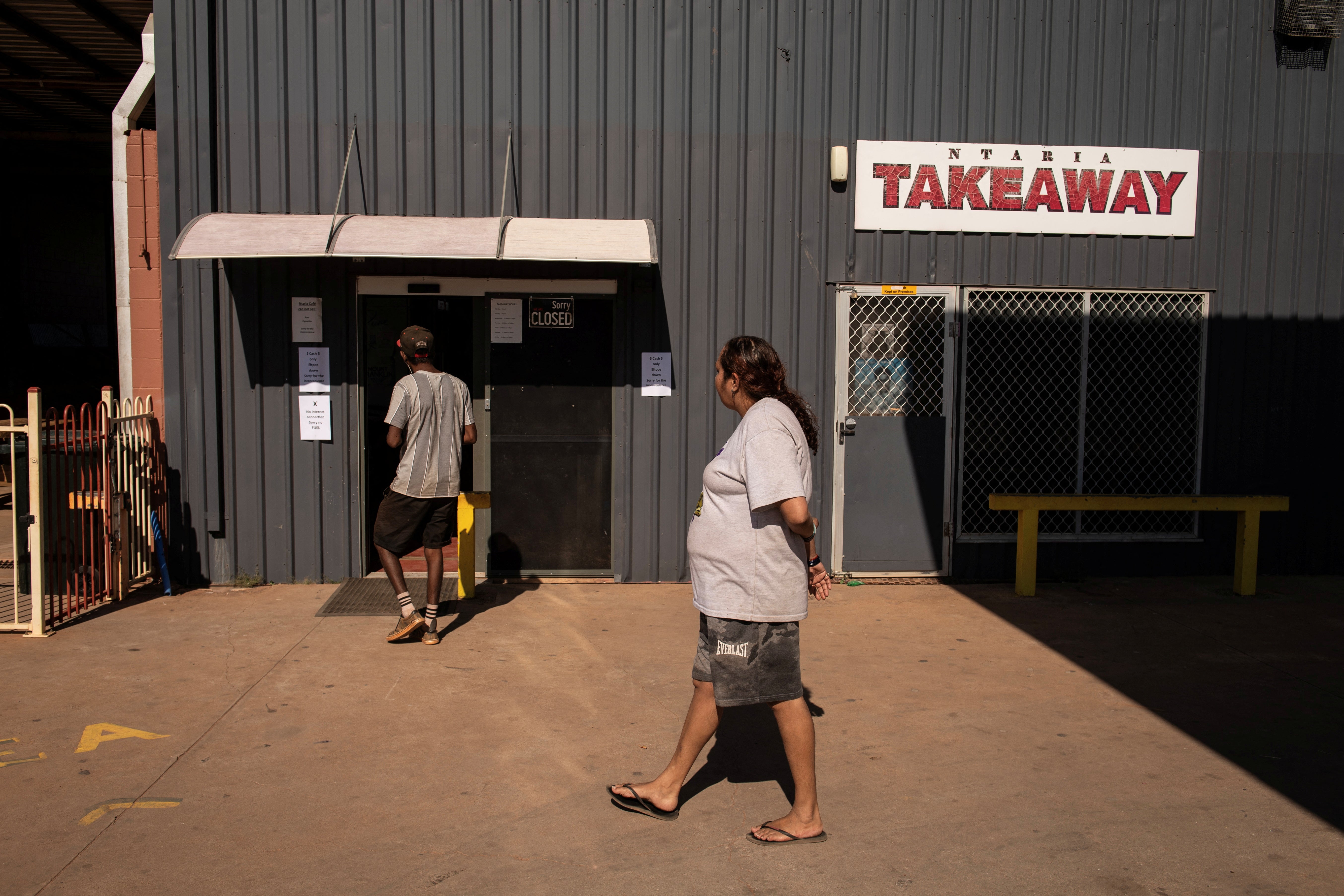 Local residents Jonathan and Rosemary walk by the takeaway shop in Hermannsburg