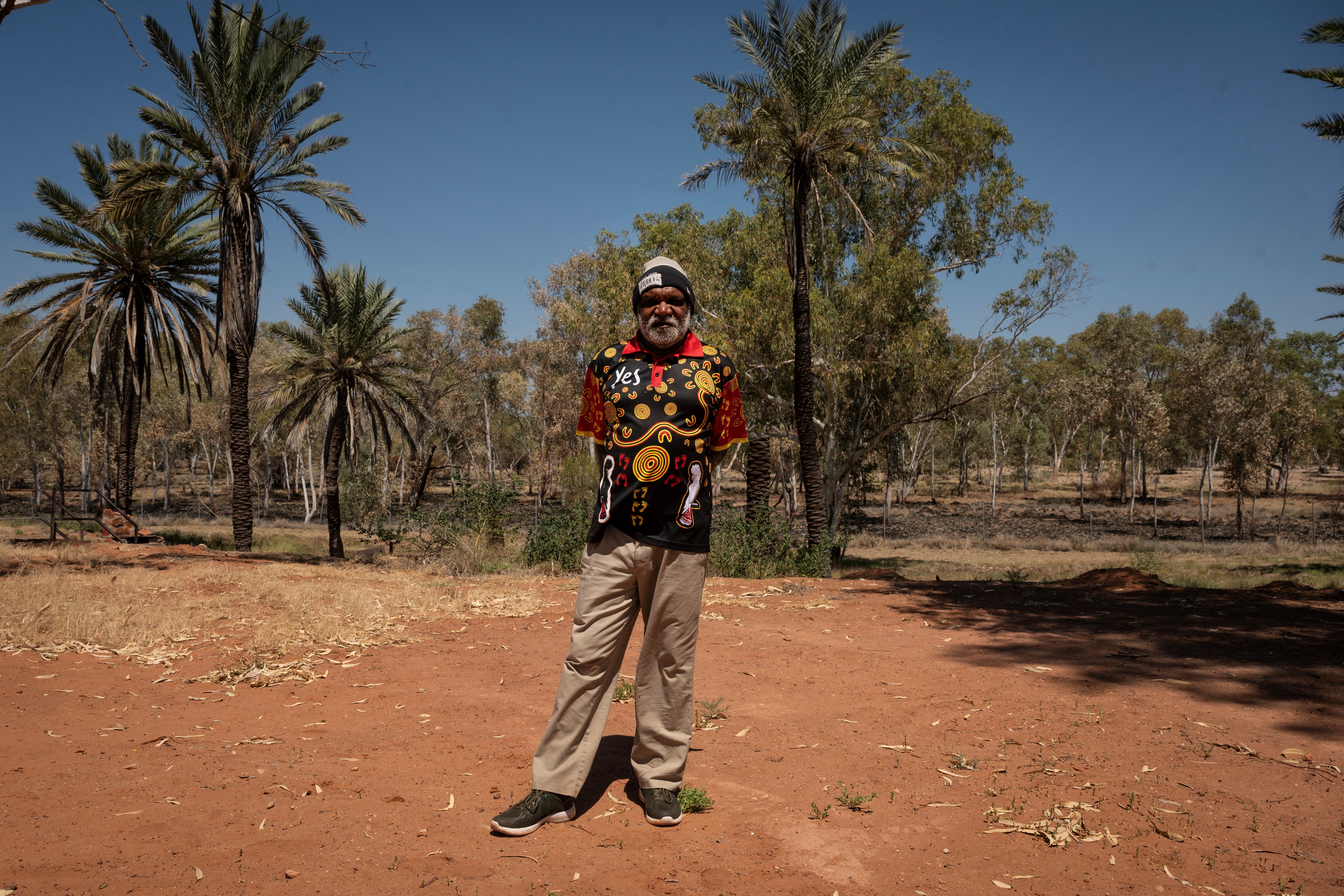 Land council worker Conrad Malcolm Ratara, 61, poses in front of the dried river bank where his ancestors lived in what is now the Hermannsburg Historic Precinct