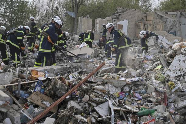 Ukrainian emergency personnel clear debris on the site of a Russian strike which hit a shop and cafe in the village