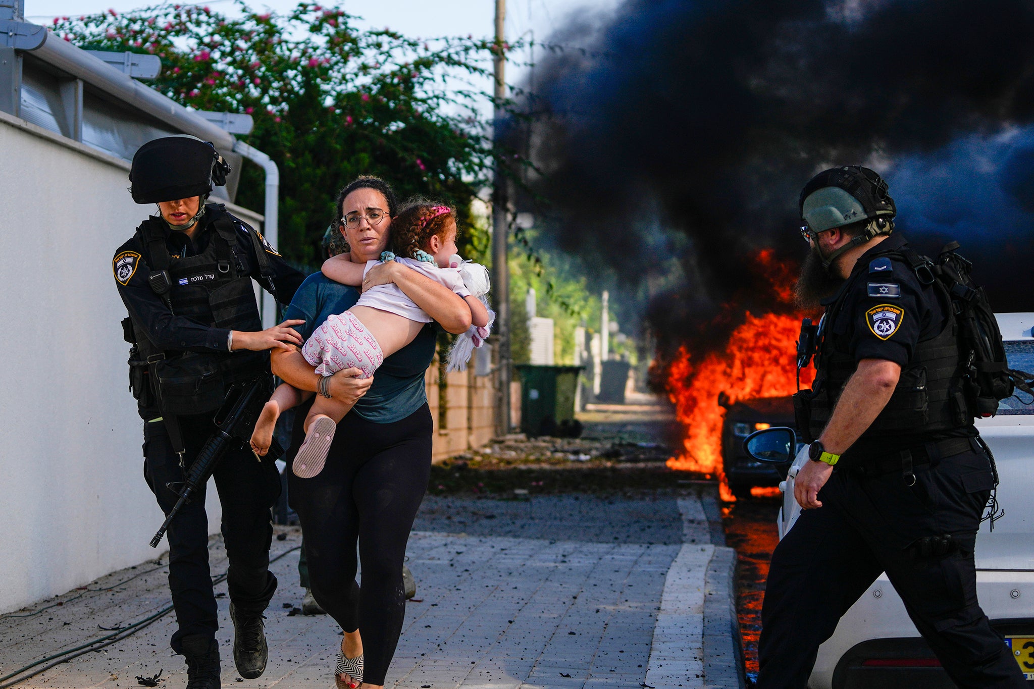 Police officers evacuate a woman and a child from a site hit by a rocket fired from the Gaza Strip