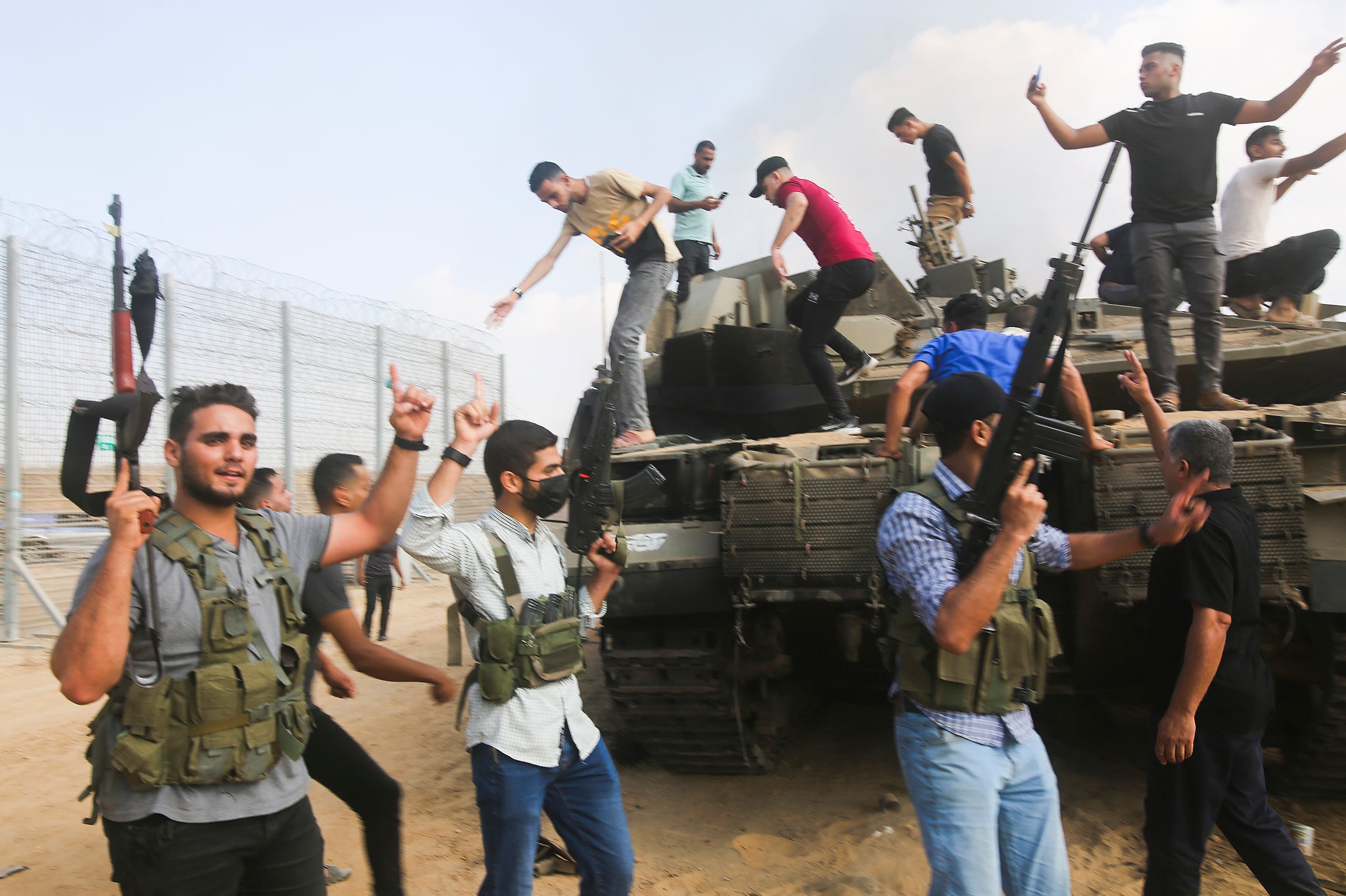 Palestinian militants celebrate by an Israeli tank at the border fence of the Gaza Strip on Saturday