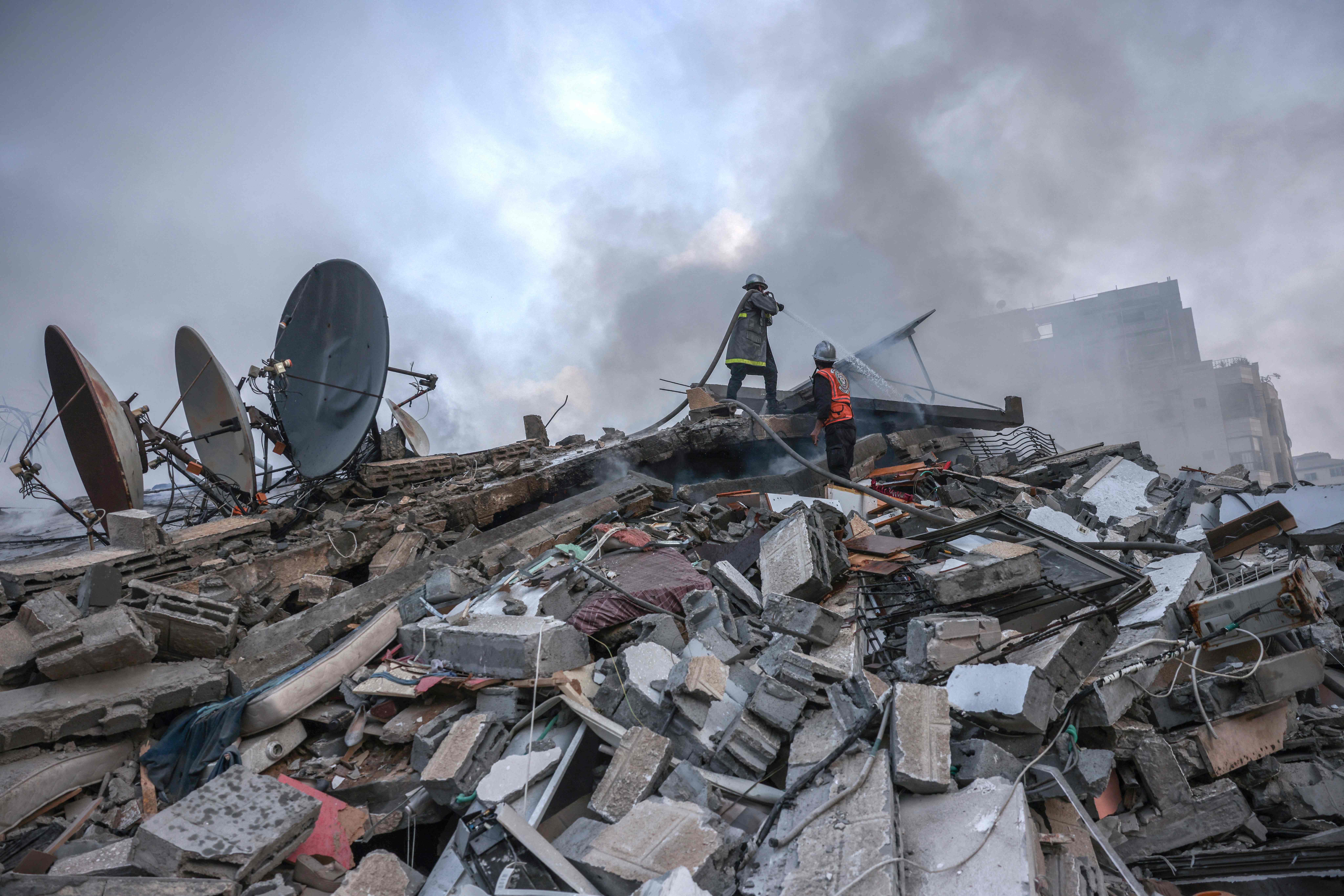 Palestinian firemen extinguish a fire that was raging in a residential building destroyed by Israeli airstrikes in Gaza City on Sunday