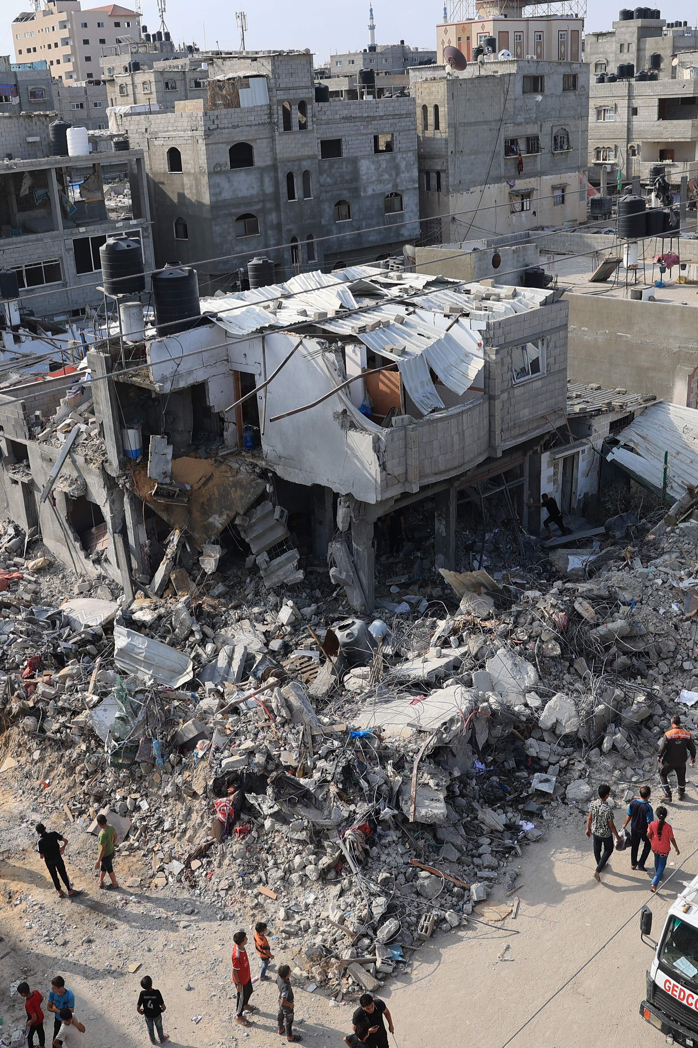 Palestinians gather around the rubble of buildings hit during Israeli airstrikes on Rafah in the southern Gaza Strip