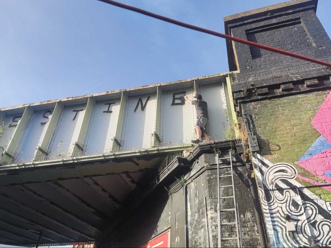 A man covers up Free Palestine message daubed in Golders Green