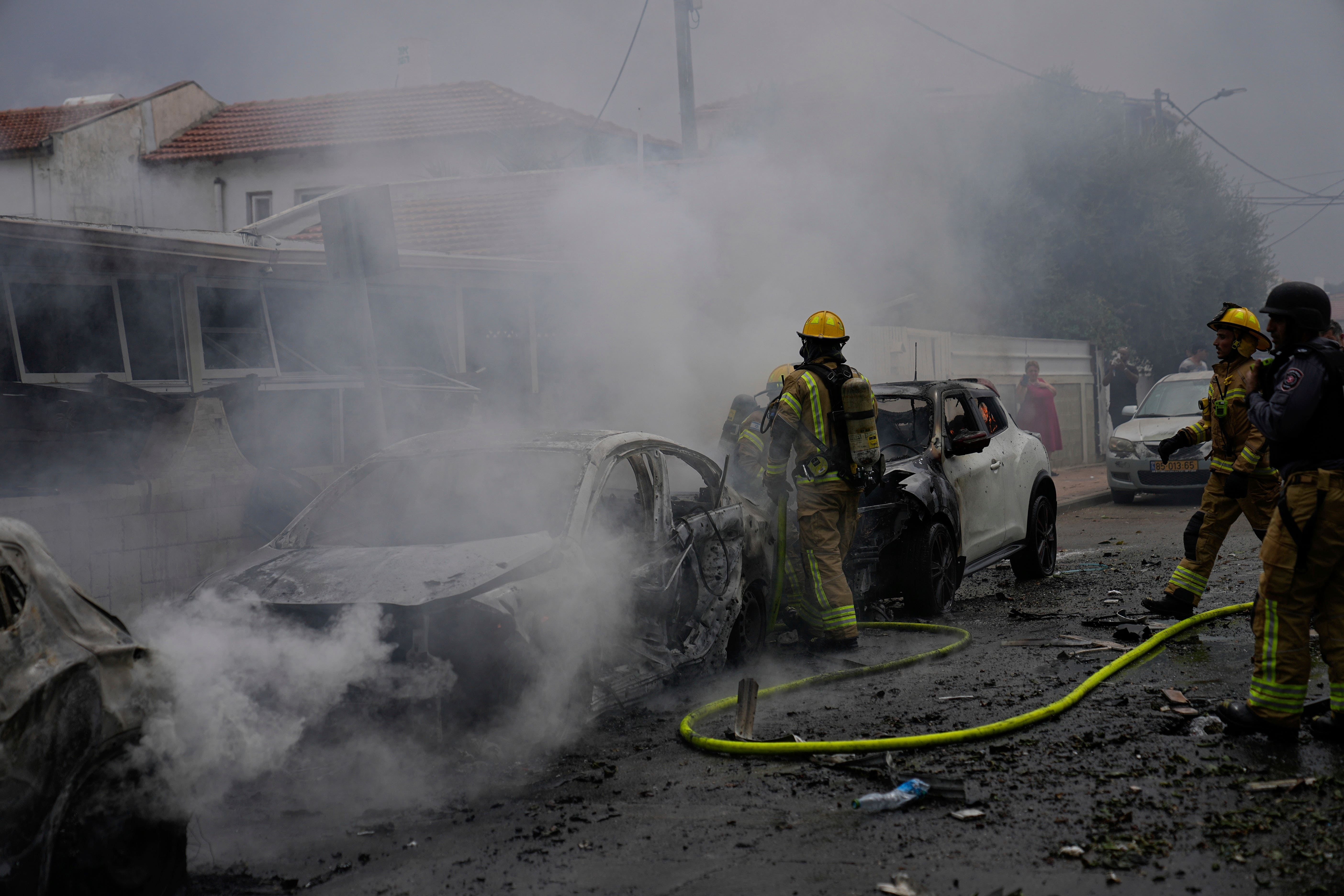 Israeli firefighters at a site struck by a rocket fired from the Gaza Strip (Ohad Zwigenberg/AP)