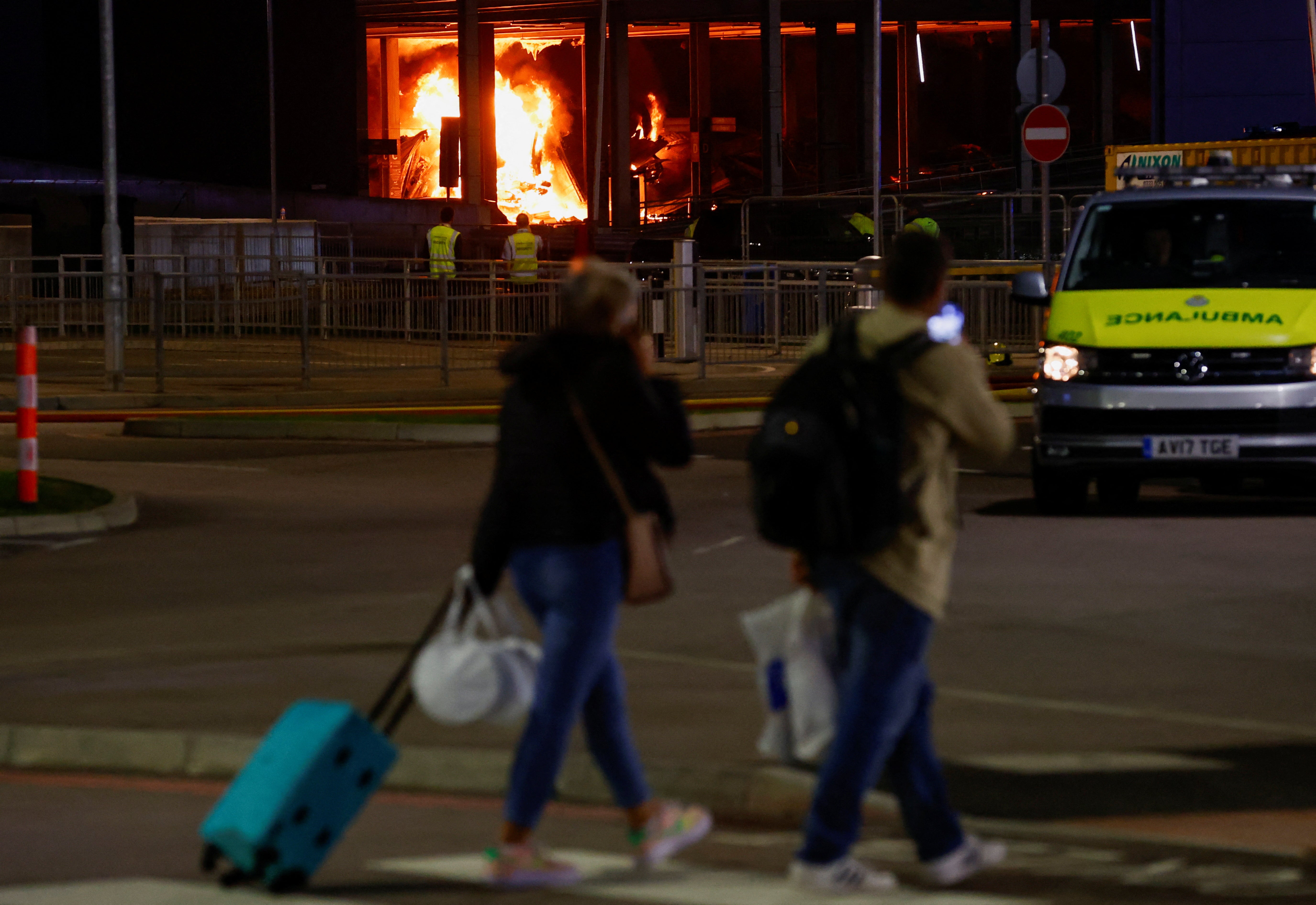 People leave as emergency services respond to a fire in Terminal Car Park 2 at Luton Airport