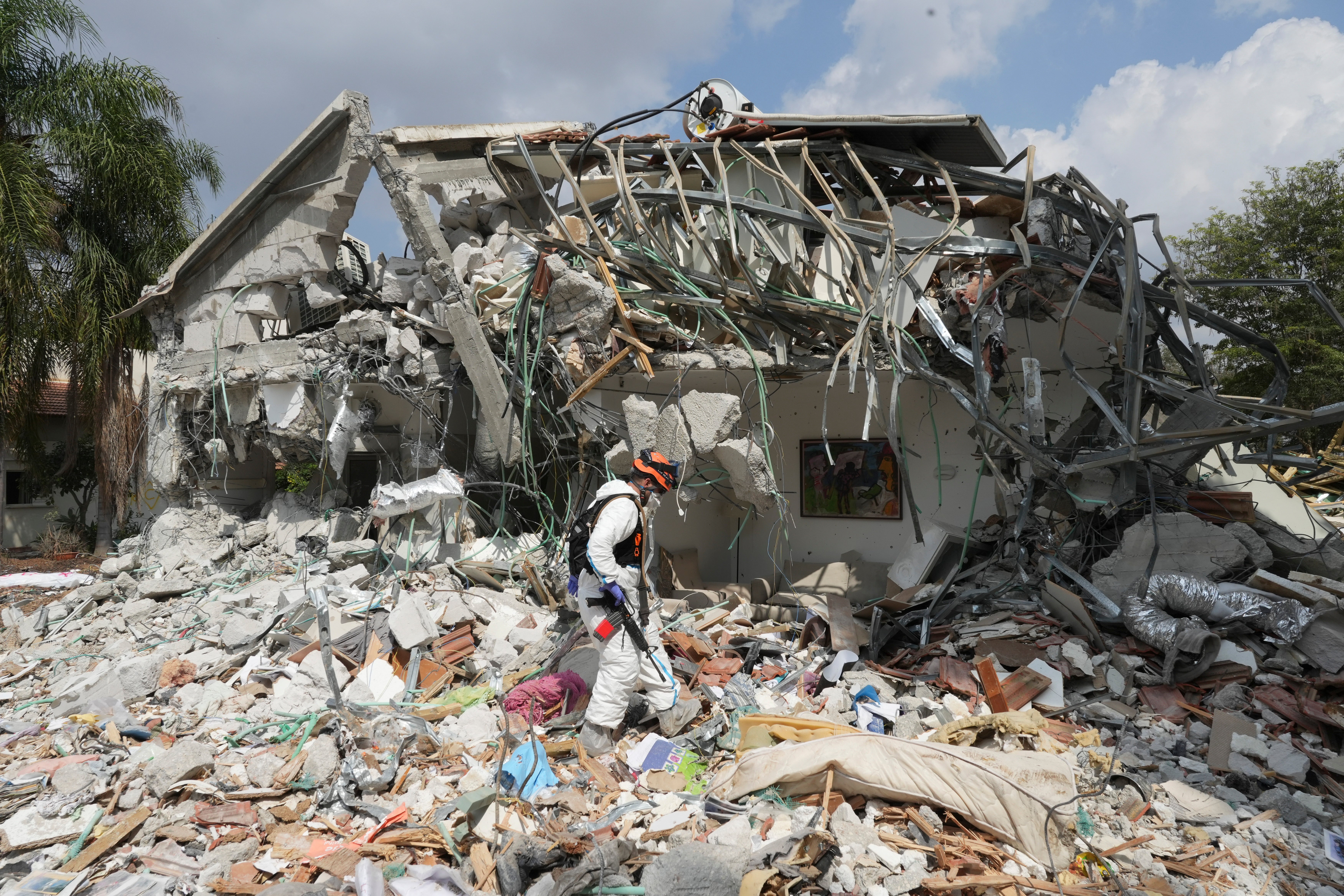 An Israeli soldier walks past a house destroyed by Hamas militants in Kibbutz Be'eri