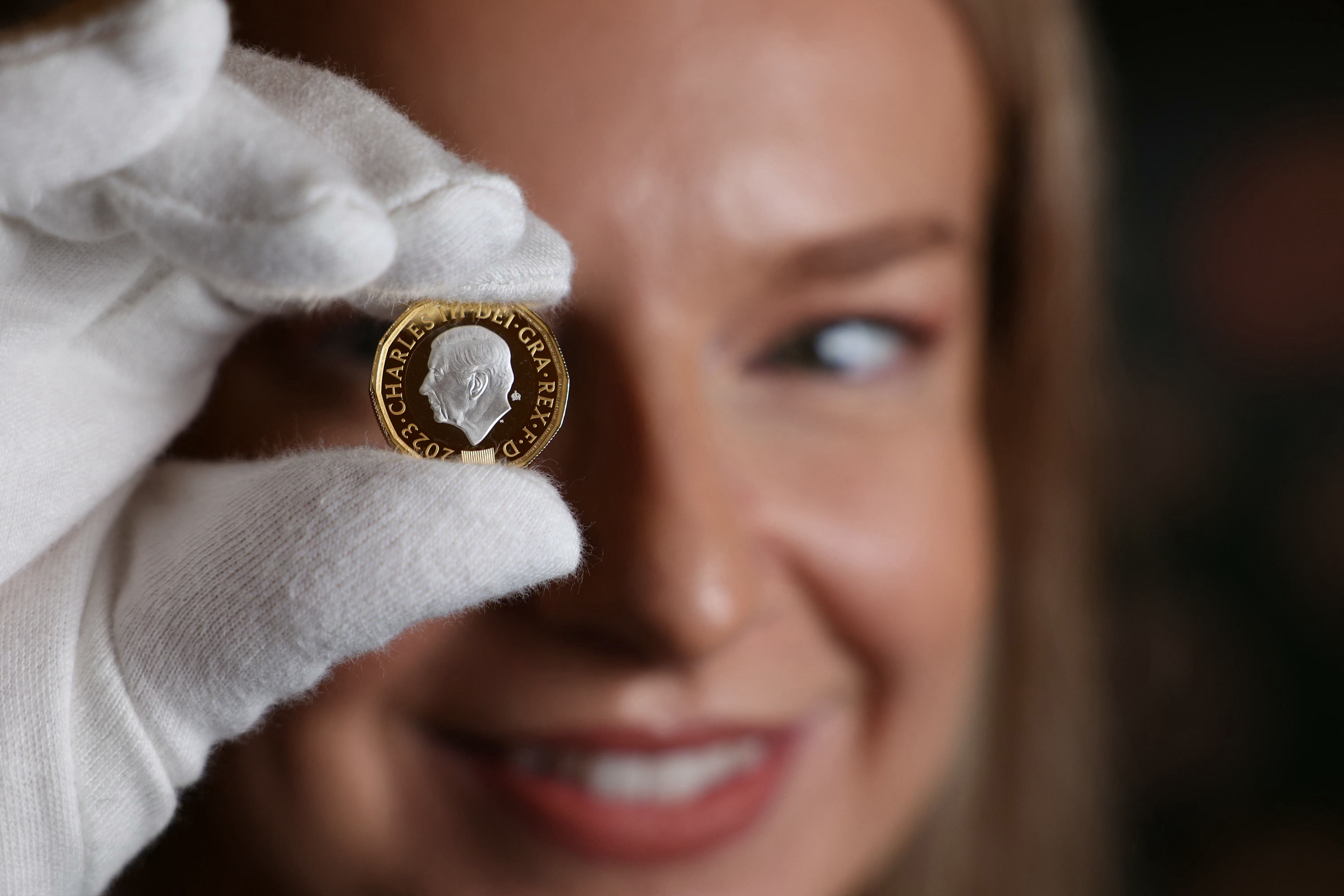 A Royal Mint assistant holds up the new £1 coin with King Charles’ image on the ‘heads’ side