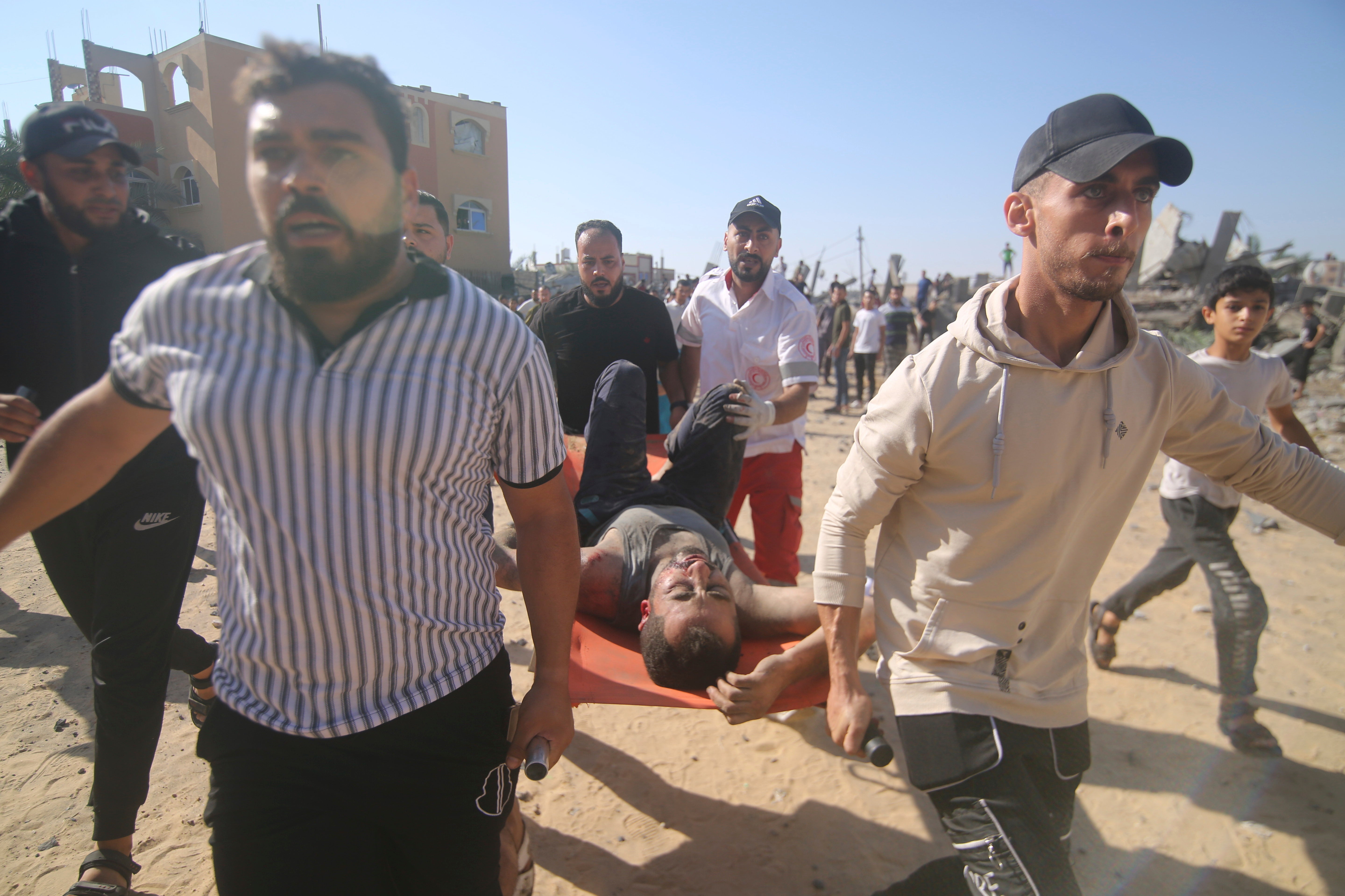 Palestinians carry an injured man from the rubble of a collapsed building after an airstrike in Rafah, in the Gaza Strip