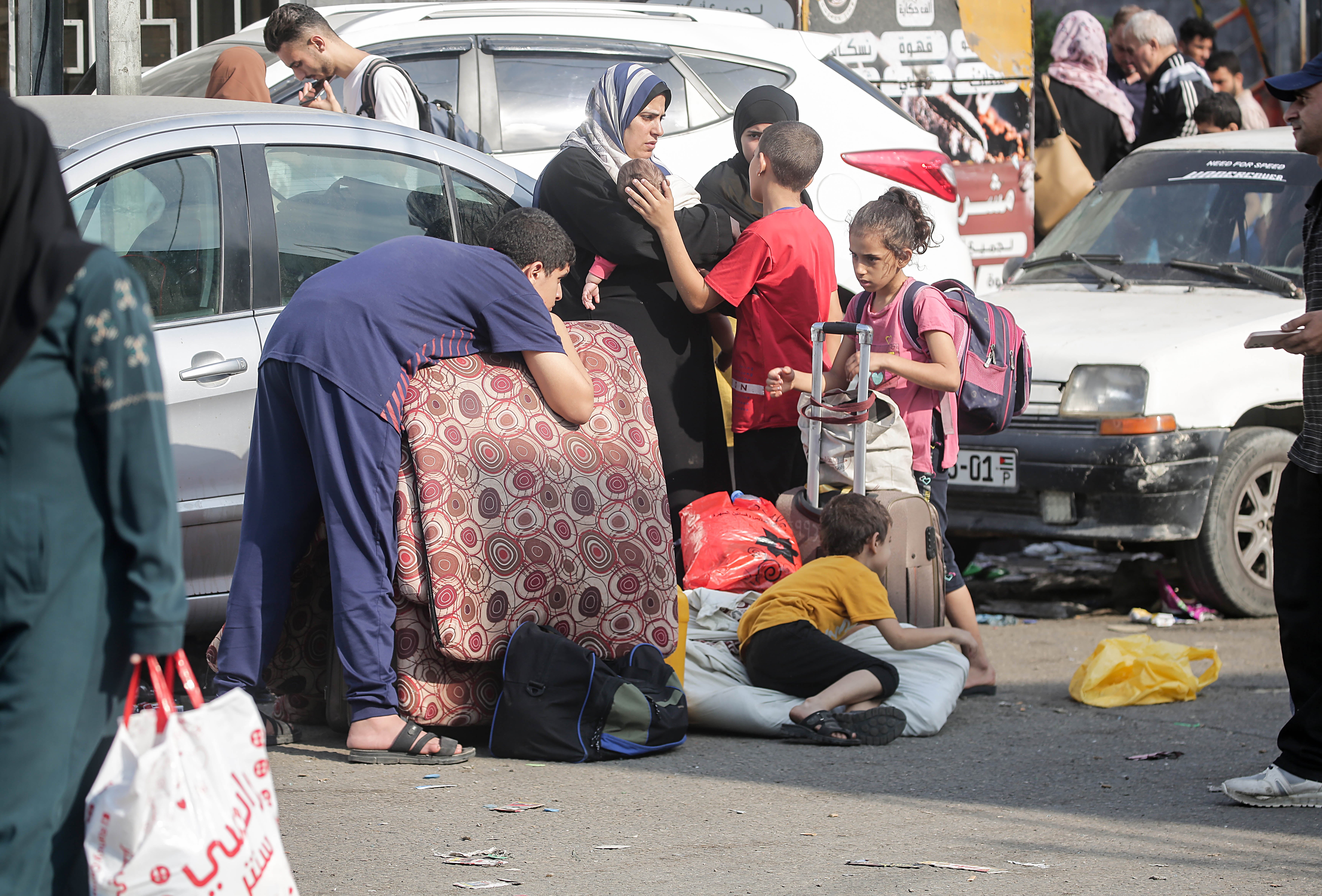 A family stand in the road carrying their belongings as they flee