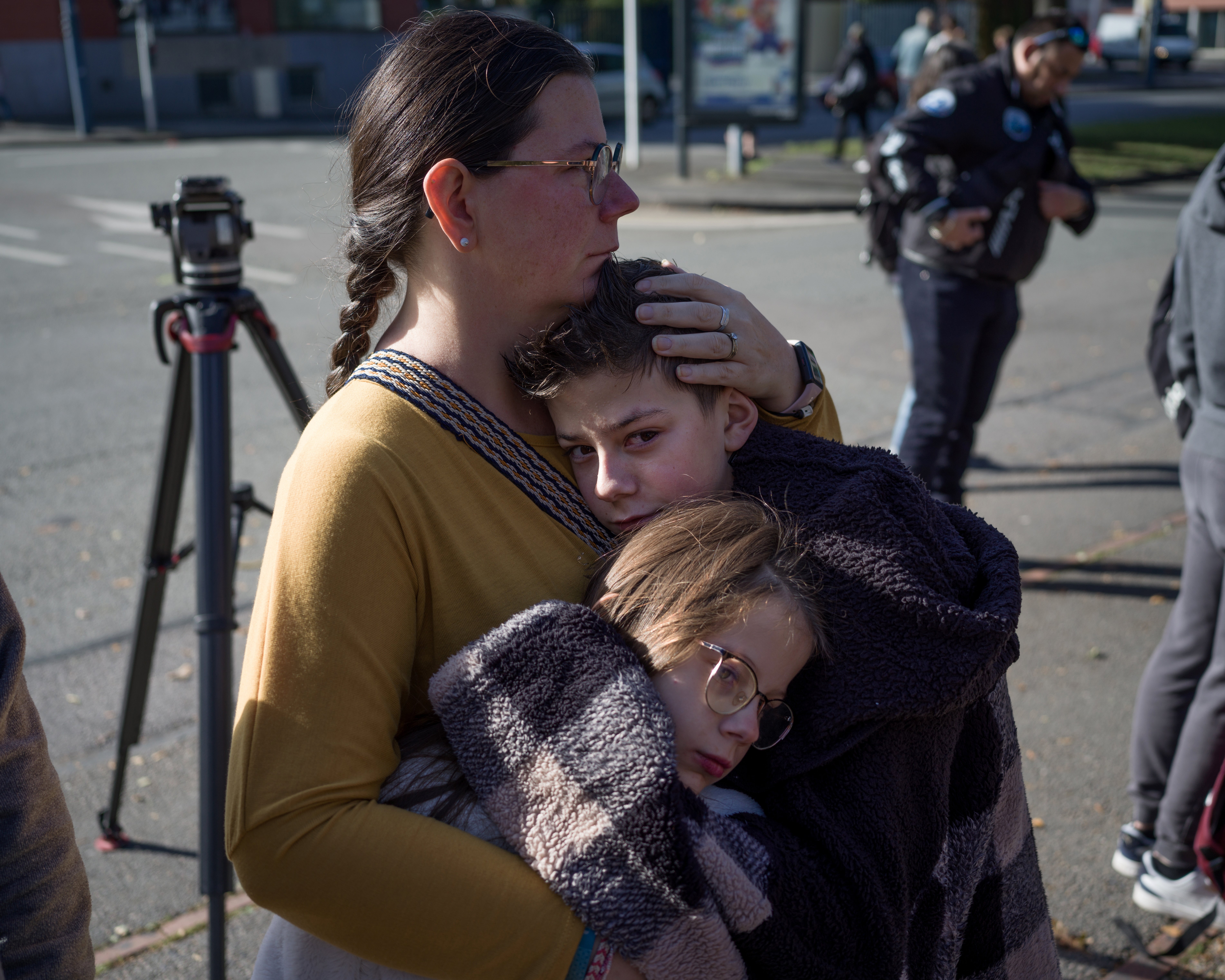 A woman comforts her children at the door of the Gambetta-Carnot public school on Saturday after the previous day’s killing in Arras