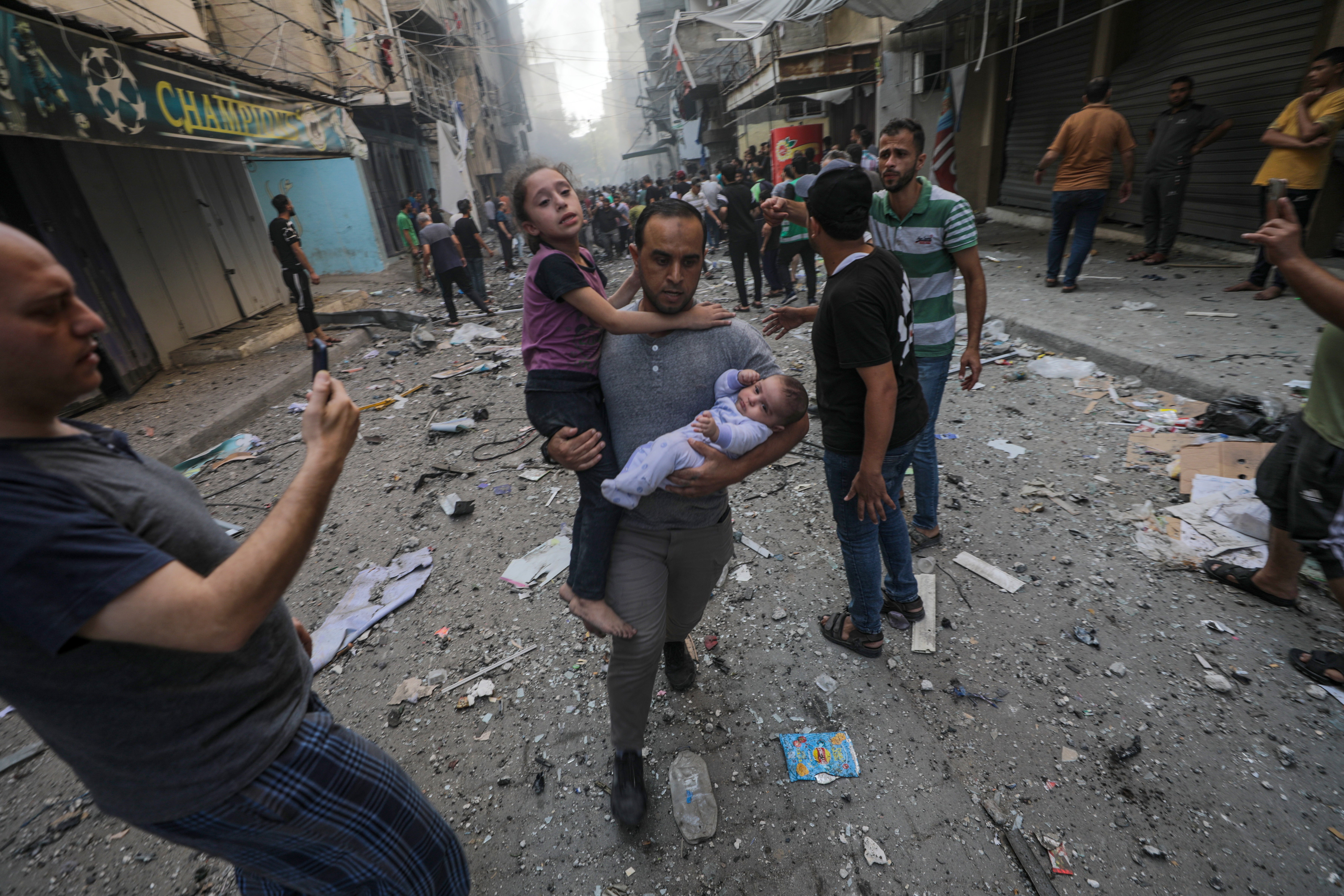 Civilians flee after the Al-Shati refugee camp is hit by rockets on Saturday