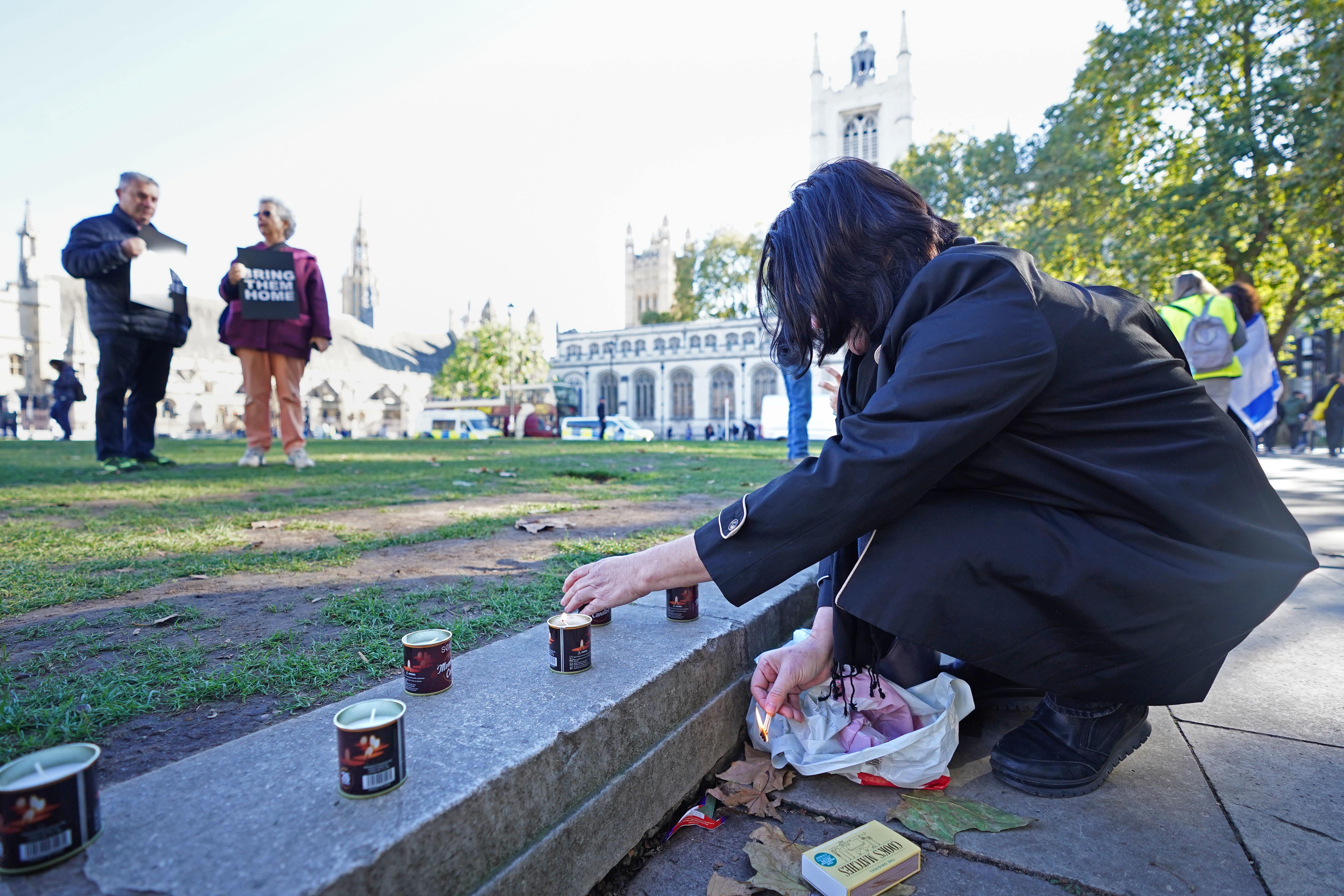 A woman lights a candle a vigil in Parliament Square, London, for victims and hostages of the Hamas attacks (James Manning/PA)