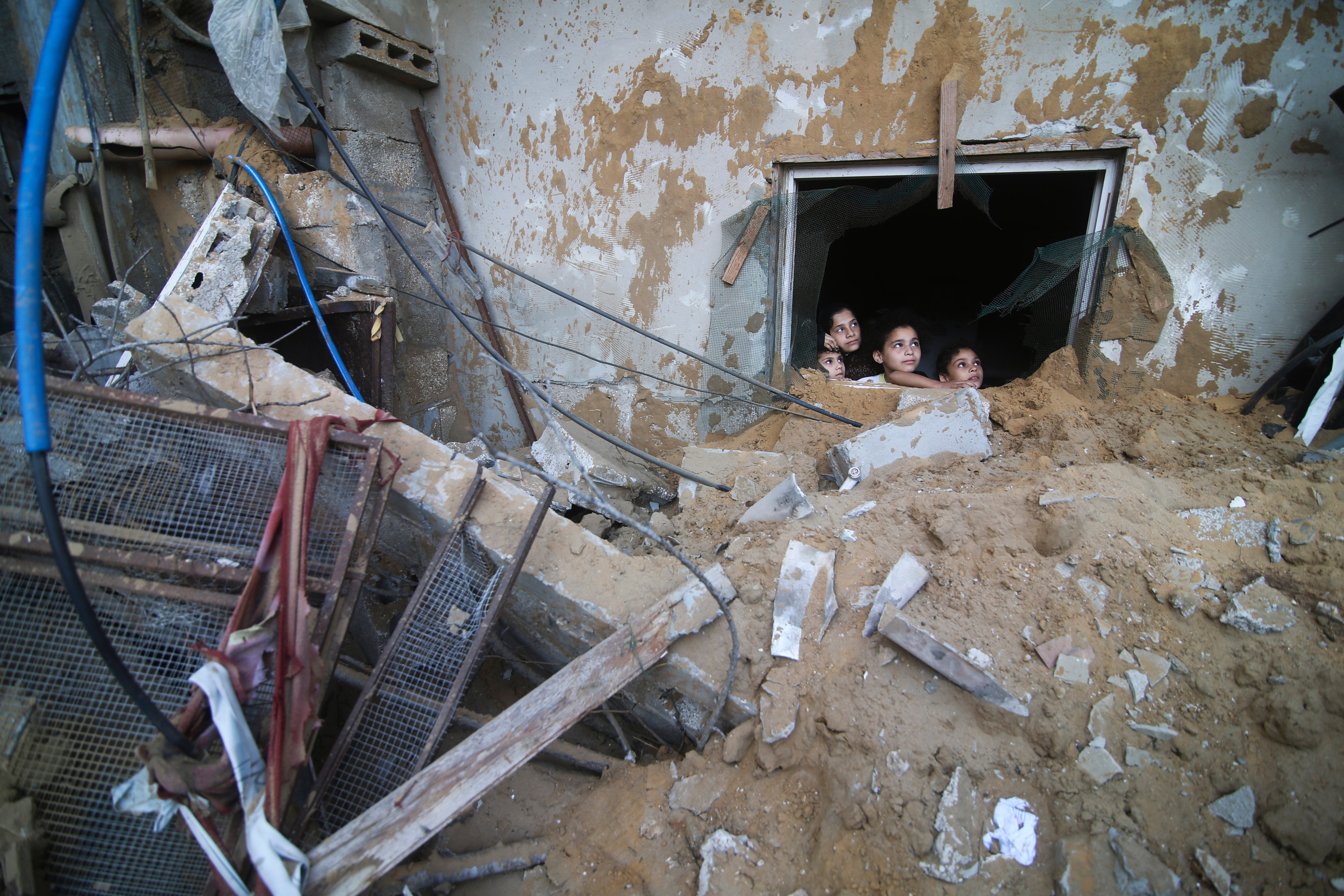 Palestinian children look at the building of the Zanon family, destroyed in Israeli airstrikes in Rafah, Gaza Strip, Saturday, 14 October 2023