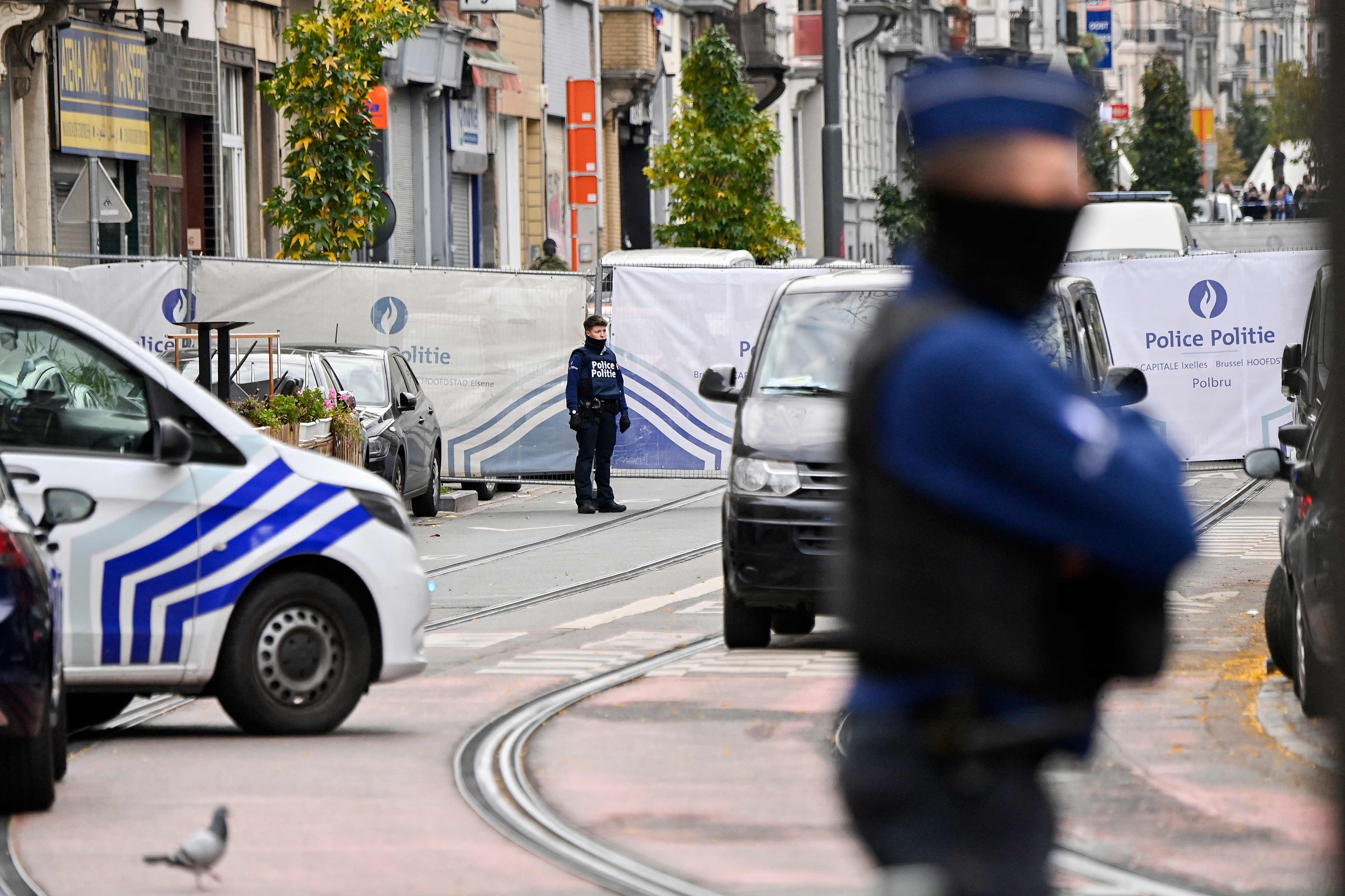 Police officers stand guard in front of the house where the suspected perpetrator of the attack was shot dead