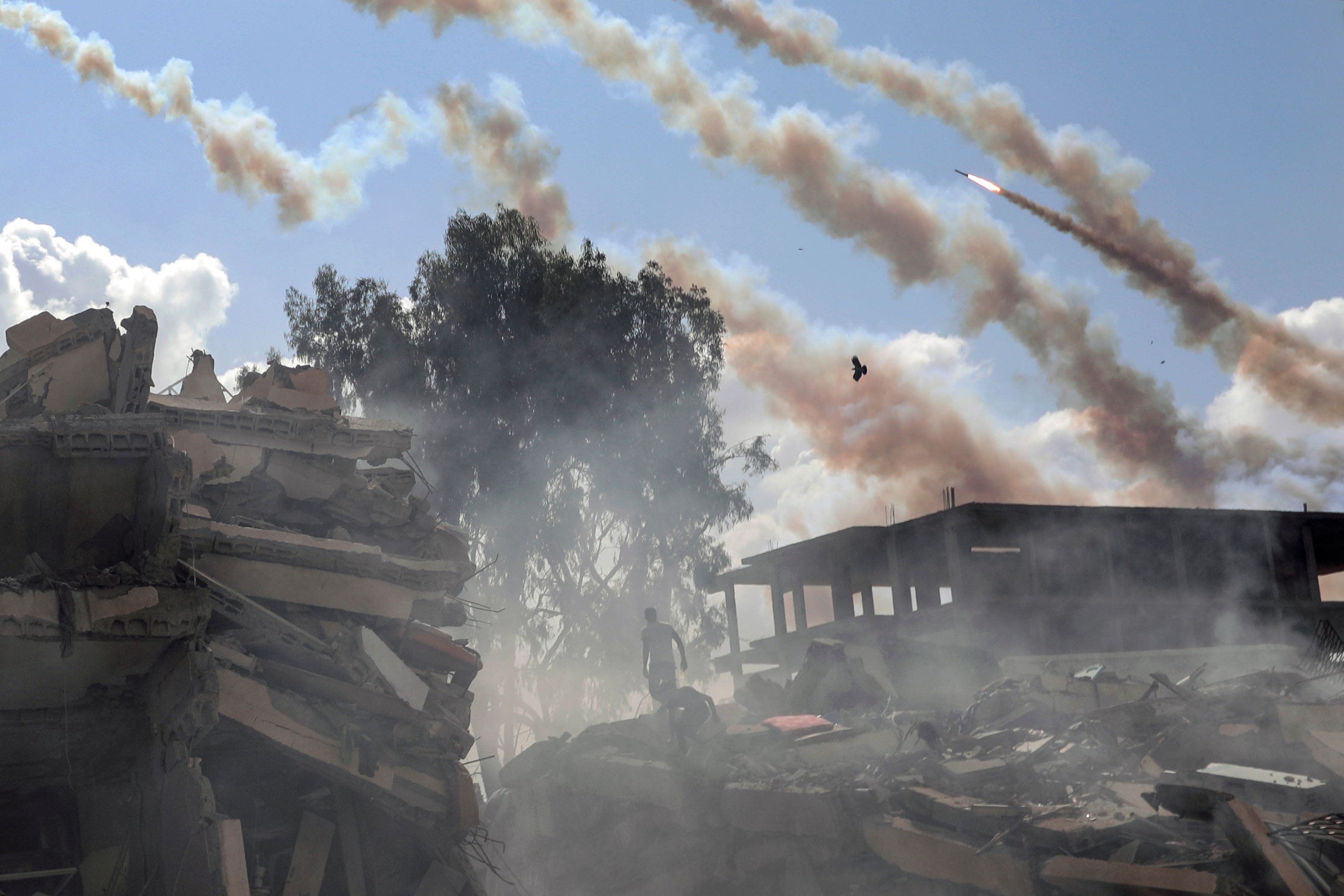 Rockets are fired from the Gaza Strip toward Israel over destroyed buildings following Israeli airstrikes on Gaza City (Mohammed Dahman/AP)