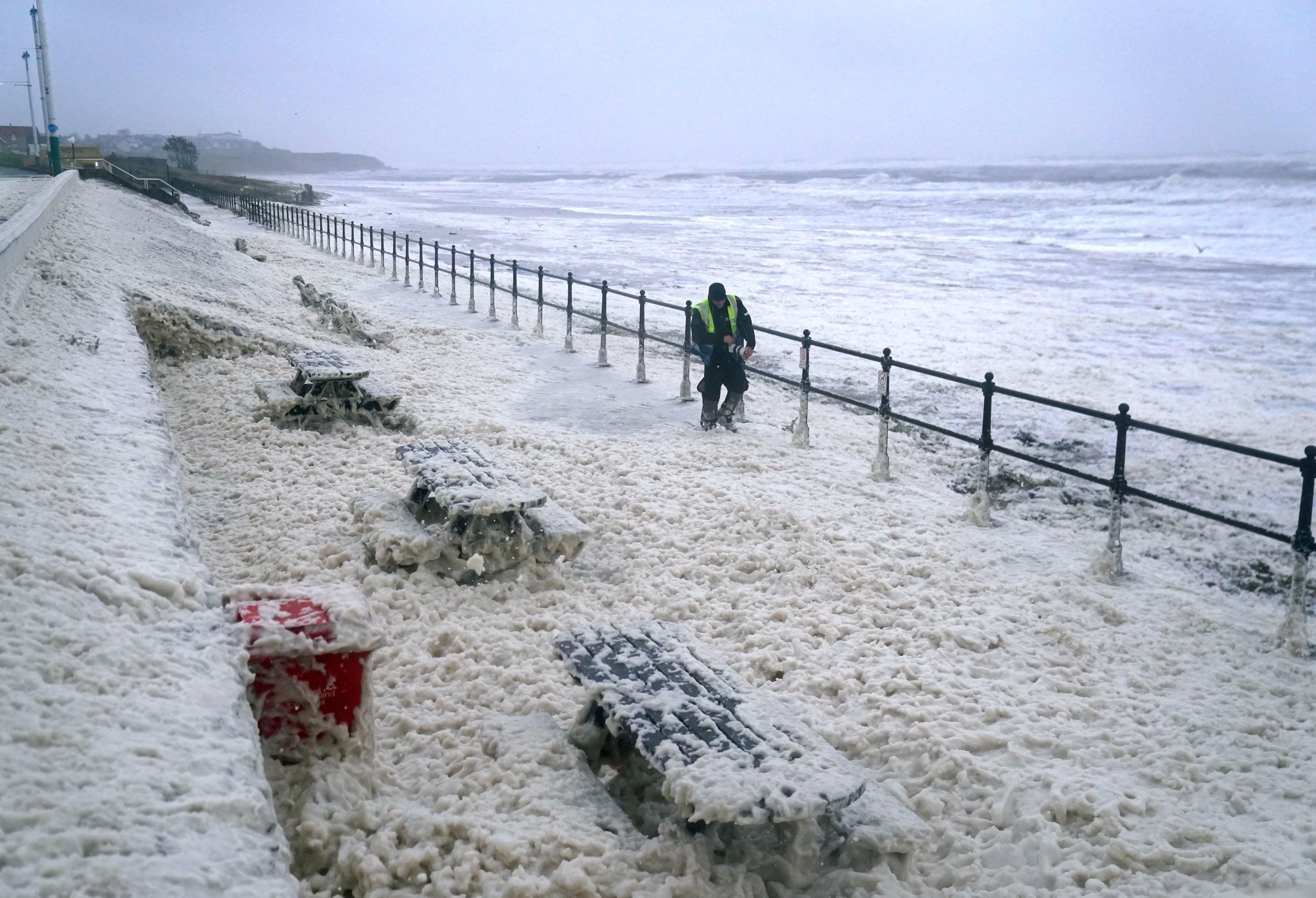 A man walks through sea foam in Seaburn, Sunderland, as Storm Babet batters the country