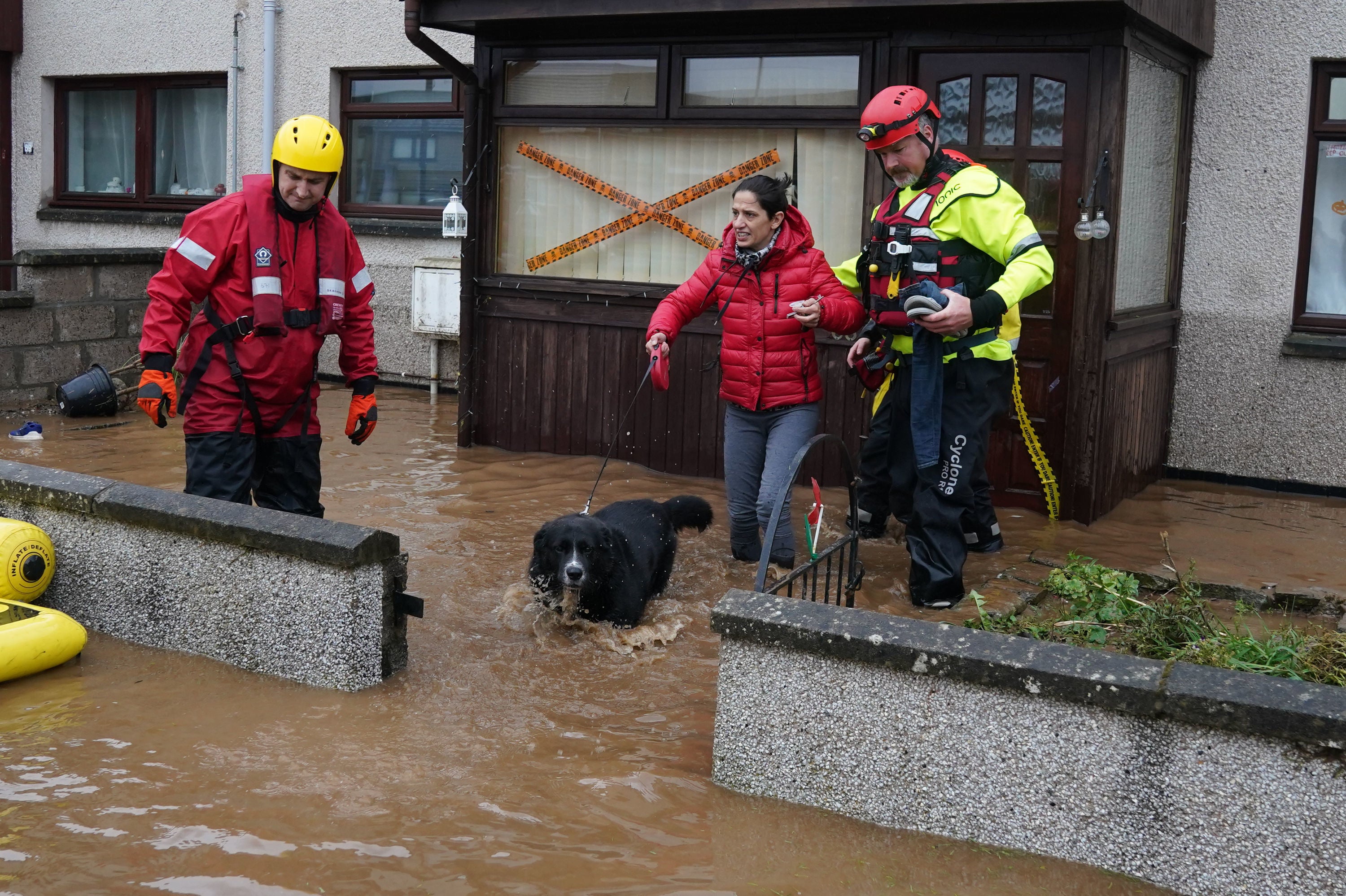 A member of the emergency services helps resident Laura Demontis from a house in Brechin