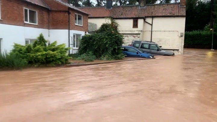 Pub and houses semi-submerged as deep floodwater rushes down road in Nottinghamshire village