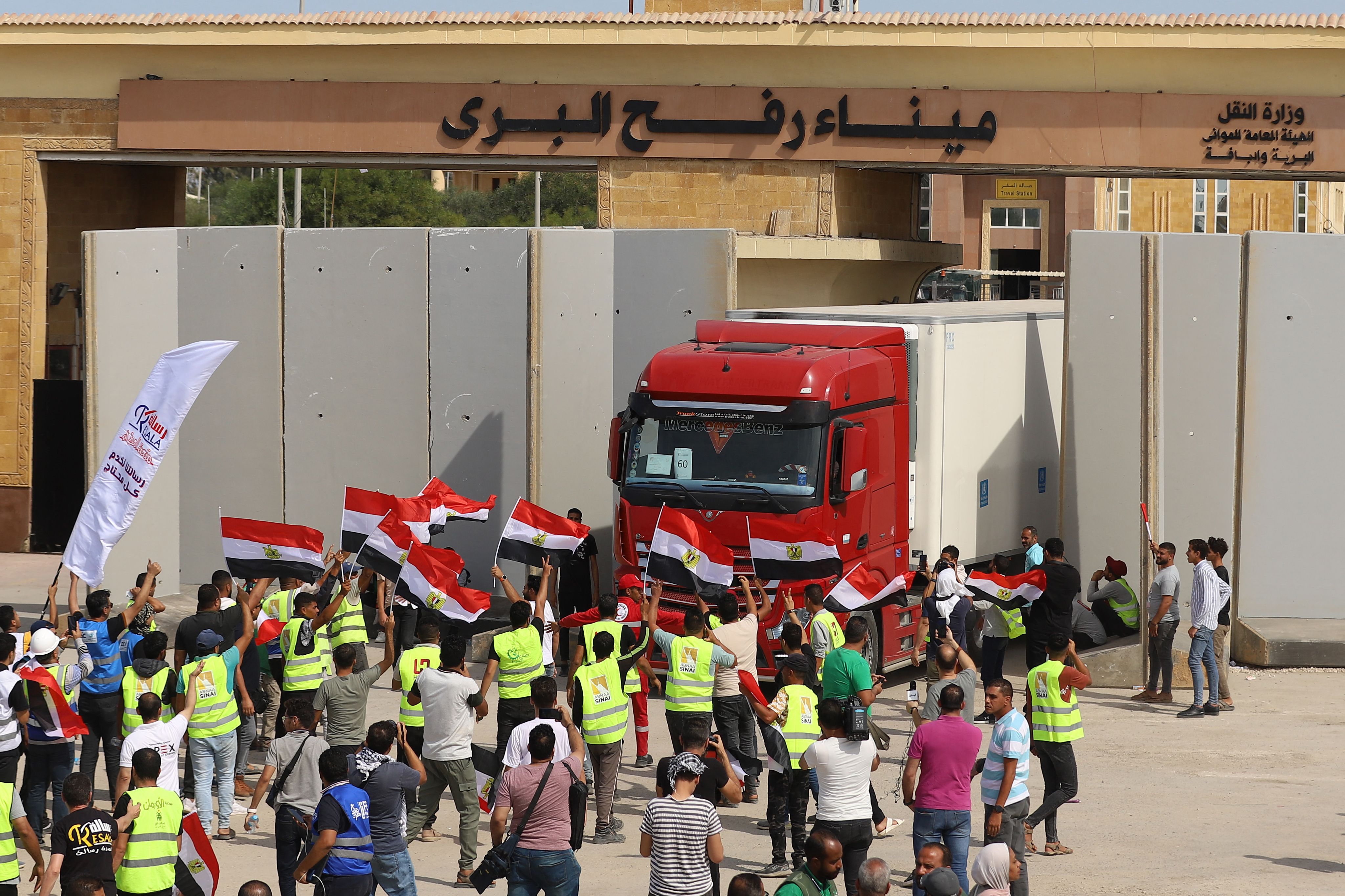 Egyptian aid workers watch as a truck crosses back into Egypt through the Rafah border crossing with Gaza on 21 October, 2023