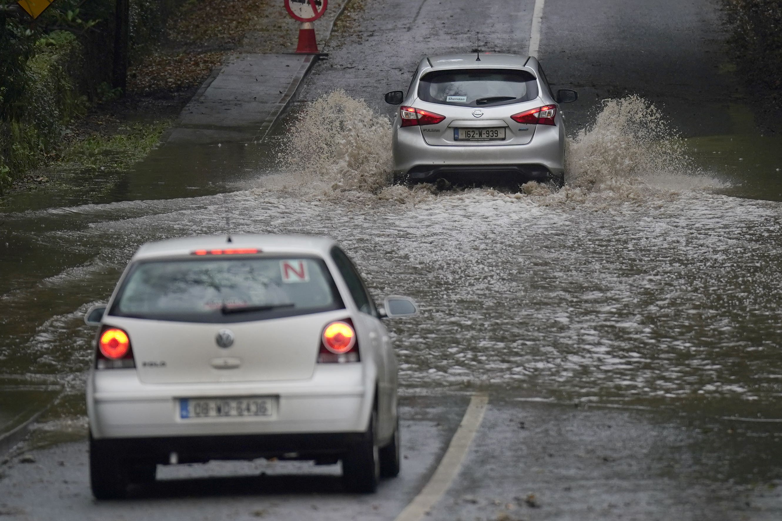 A car is driven through a flooded road in Faithlegg, Co. Waterford, Ireland, following Storm Babet (Niall Carson/PA)