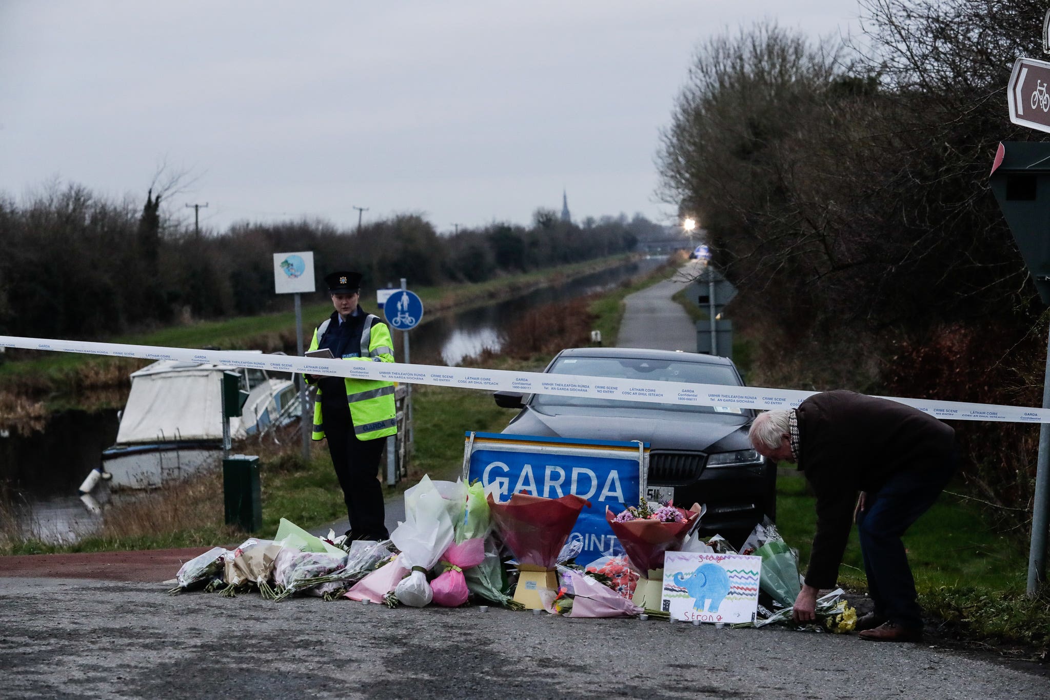 A man lays flowers with other floral tributes left near to the Grand Canal in Tullamore, County Offaly (PA)