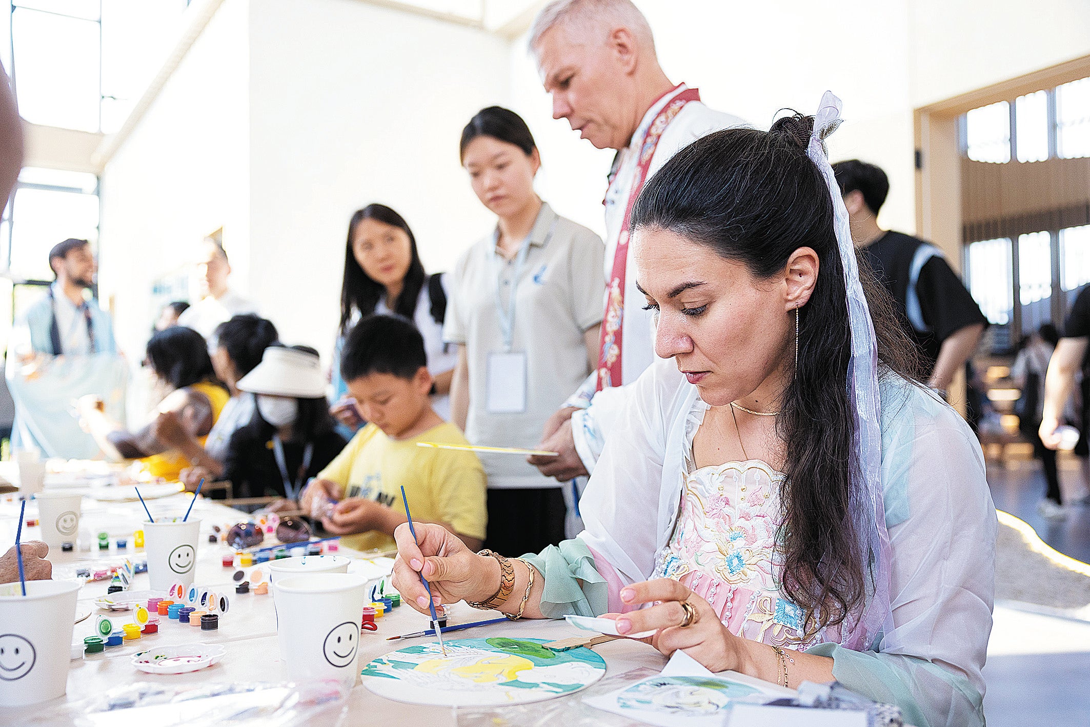 A woman dressed in hanfu paints on a Chinese fan in Huzhou, Zhejiang province