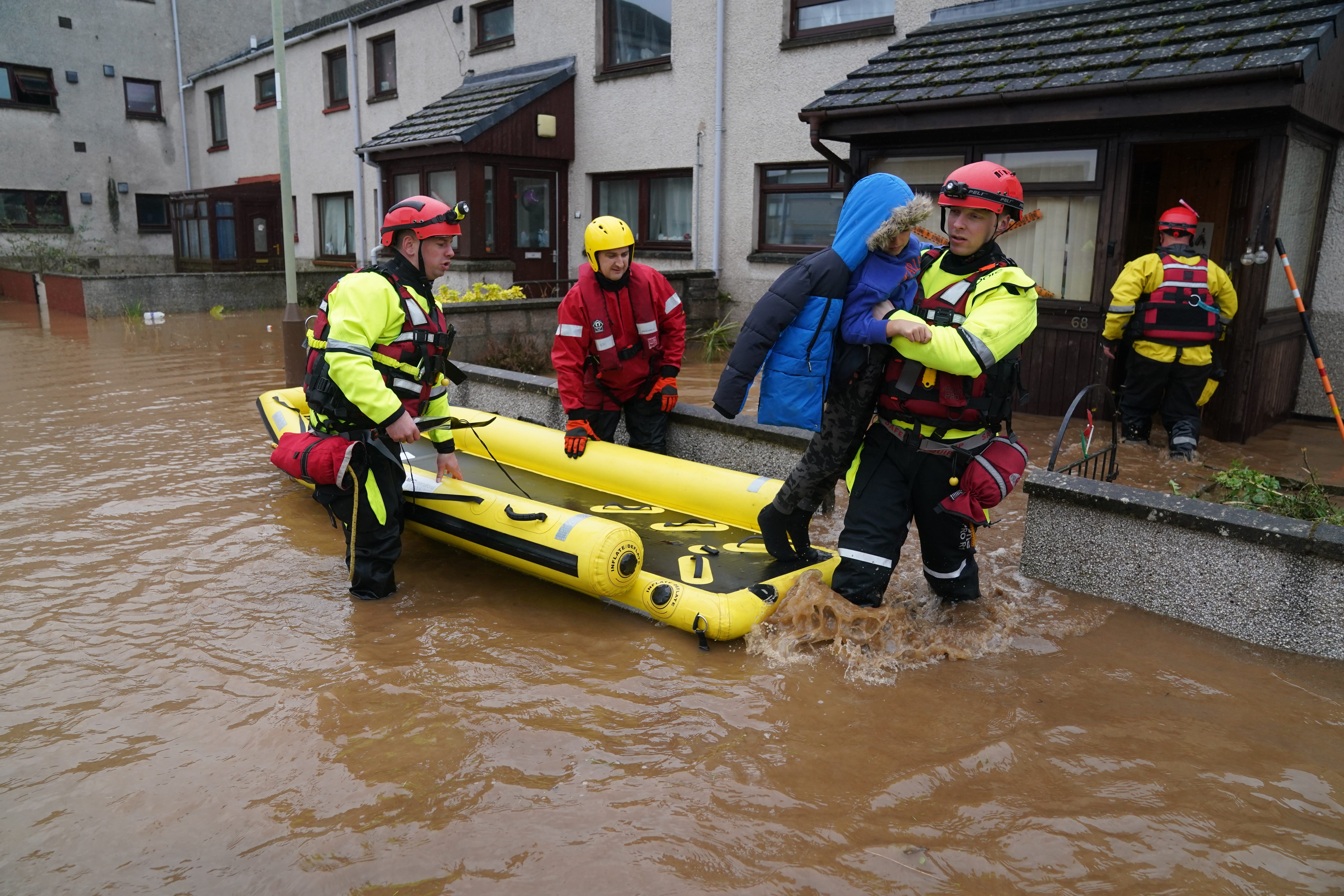 A member of the emergency services carries a boy from a house in Brechin (PA)