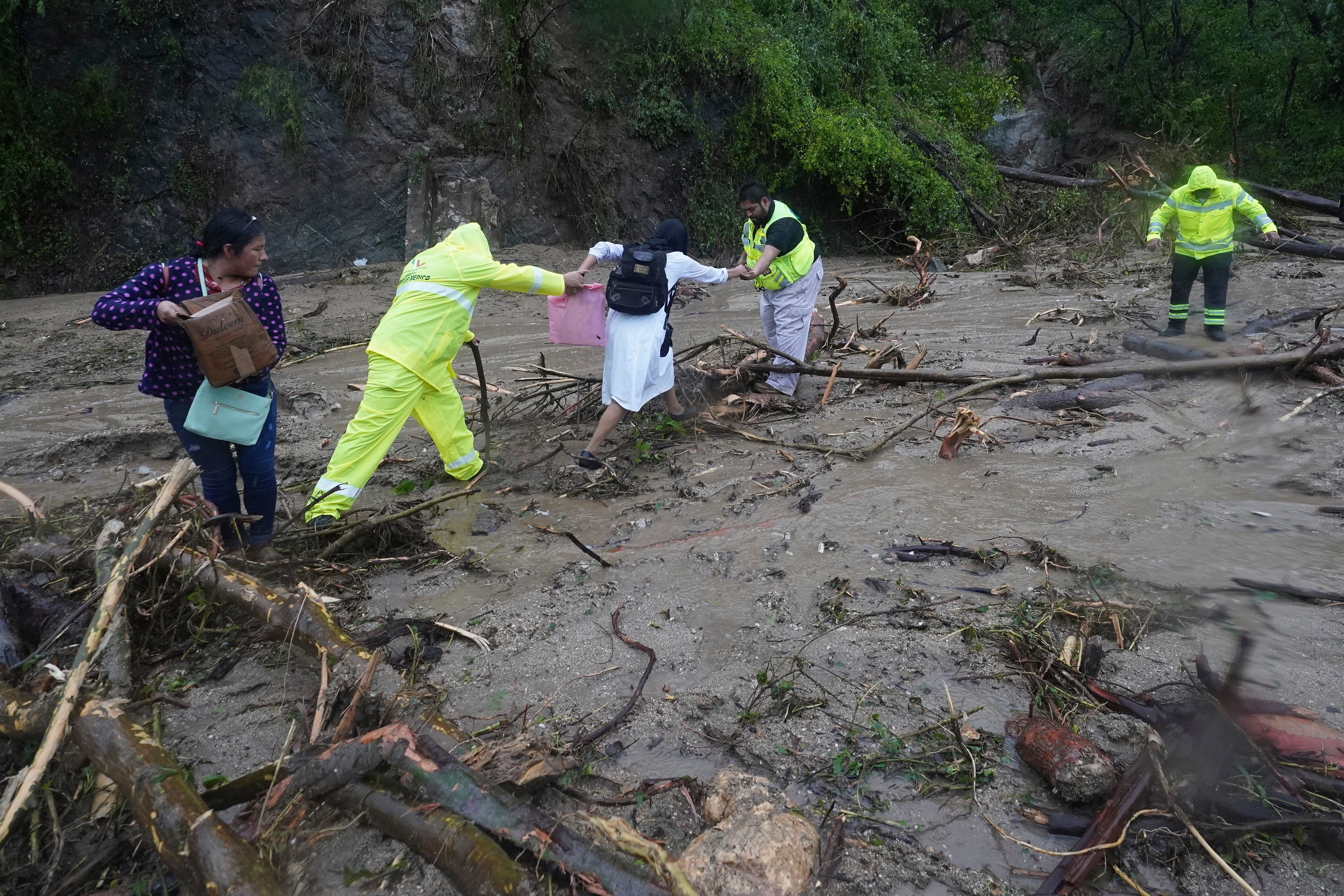 People get help crossing a highway blocked by a landslide triggered by Hurricane Otis near Acapulco, Mexico, Wednesday, Oct. 25, 2023