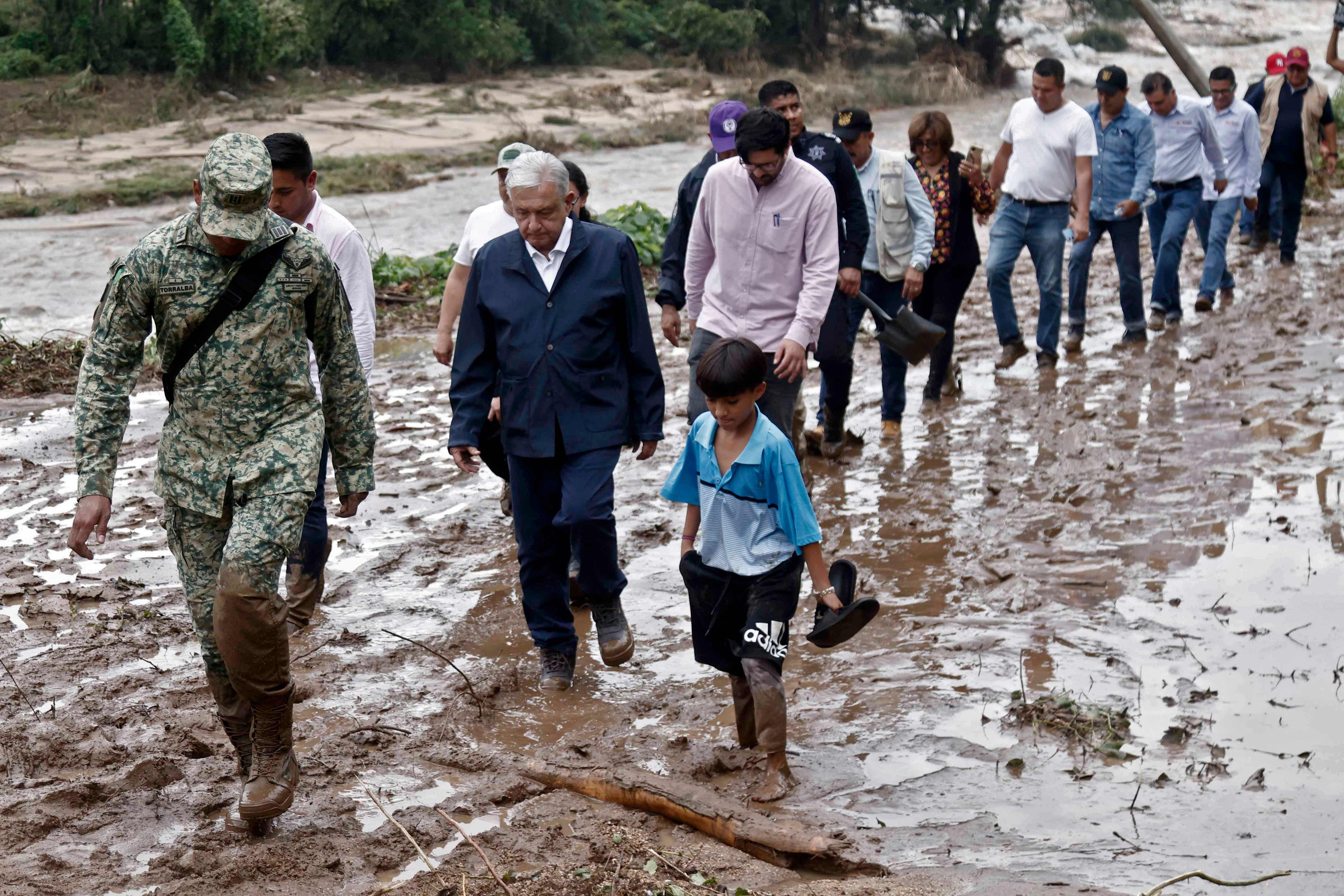 Mexico’s president Andres Manuel Lopez Obrador and members of his cabinet walk through mud as they visit a hurricane-damaged community near Acapulco on Wednesday