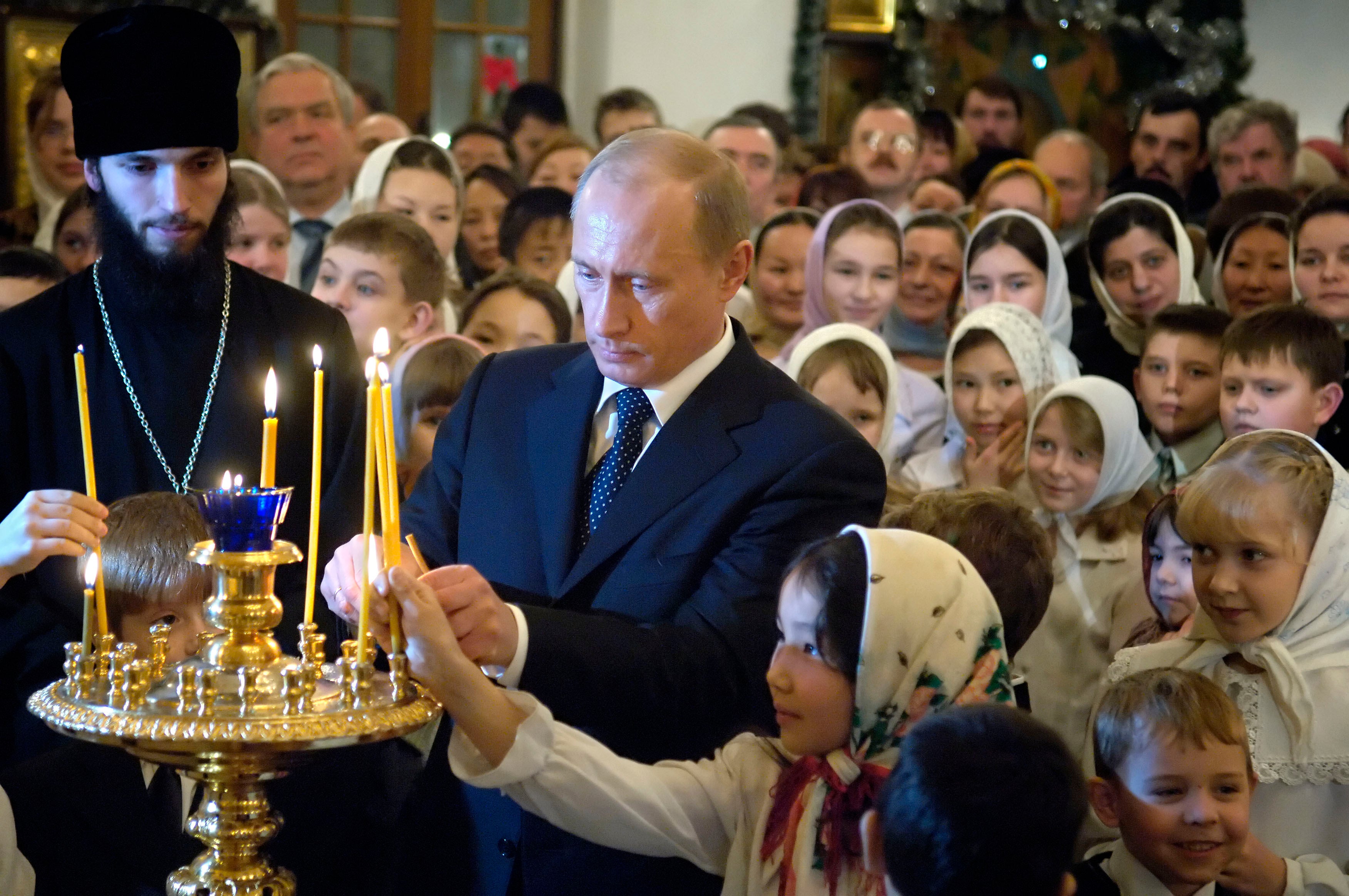 Russian President Vladimir Putin, center, surrounded by children, lights a candle during Russian Orthodox Christmas celebrations in a cathedral in the Siberian city of Yakutsk