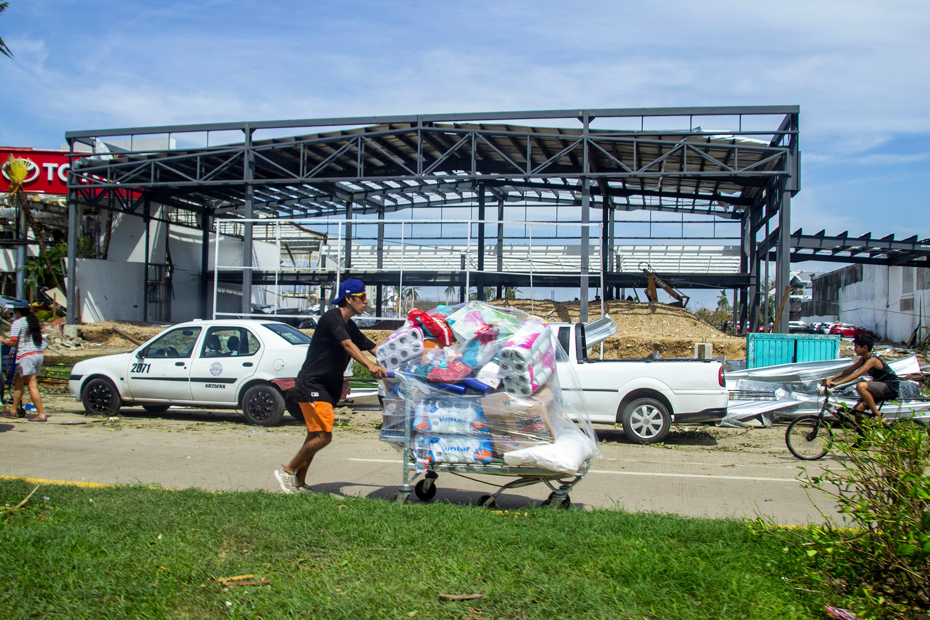 A person walks carrying goods from a looted store after hurricane Otis