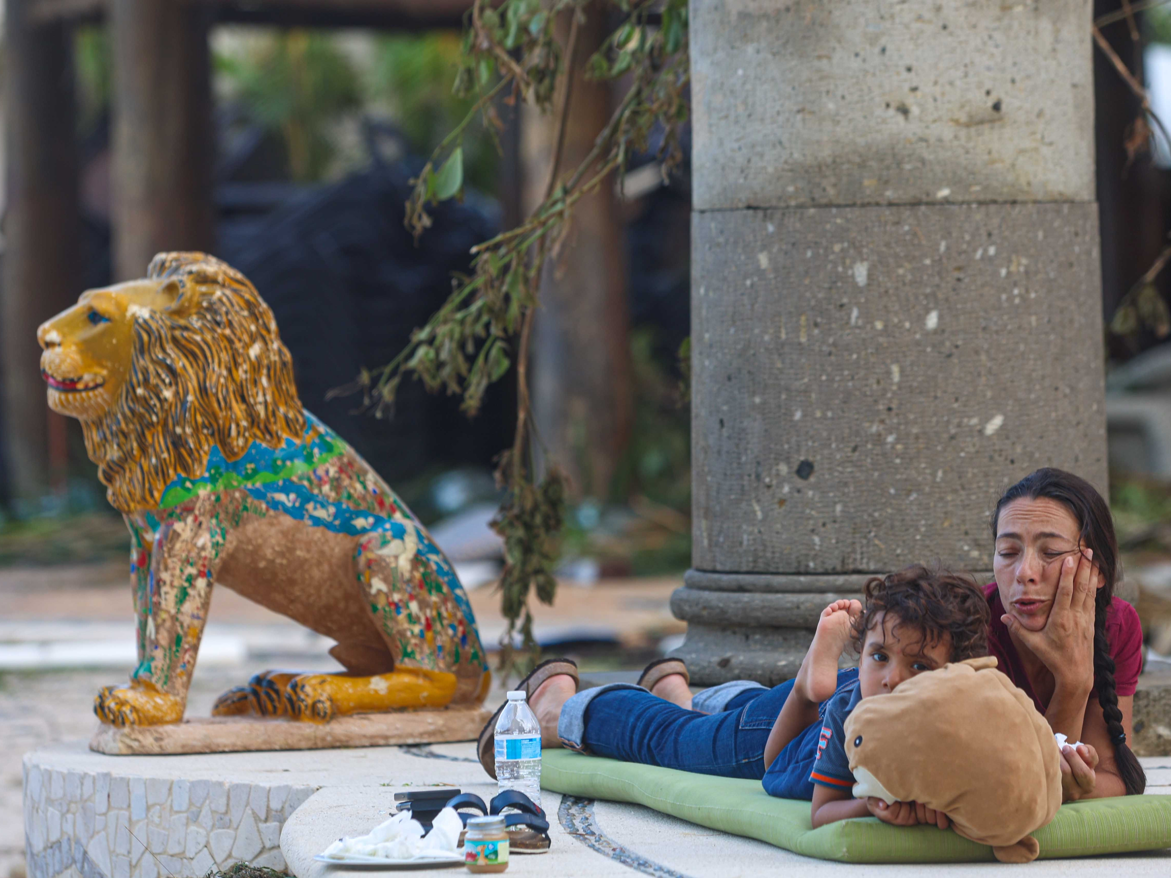 A woman rests with her son on a mat outdoors on October 26, 2023 in Acapulco, Mexico. Otis made landfall through the coast of Acapulco around midnight of October 25 as a category 5 storm