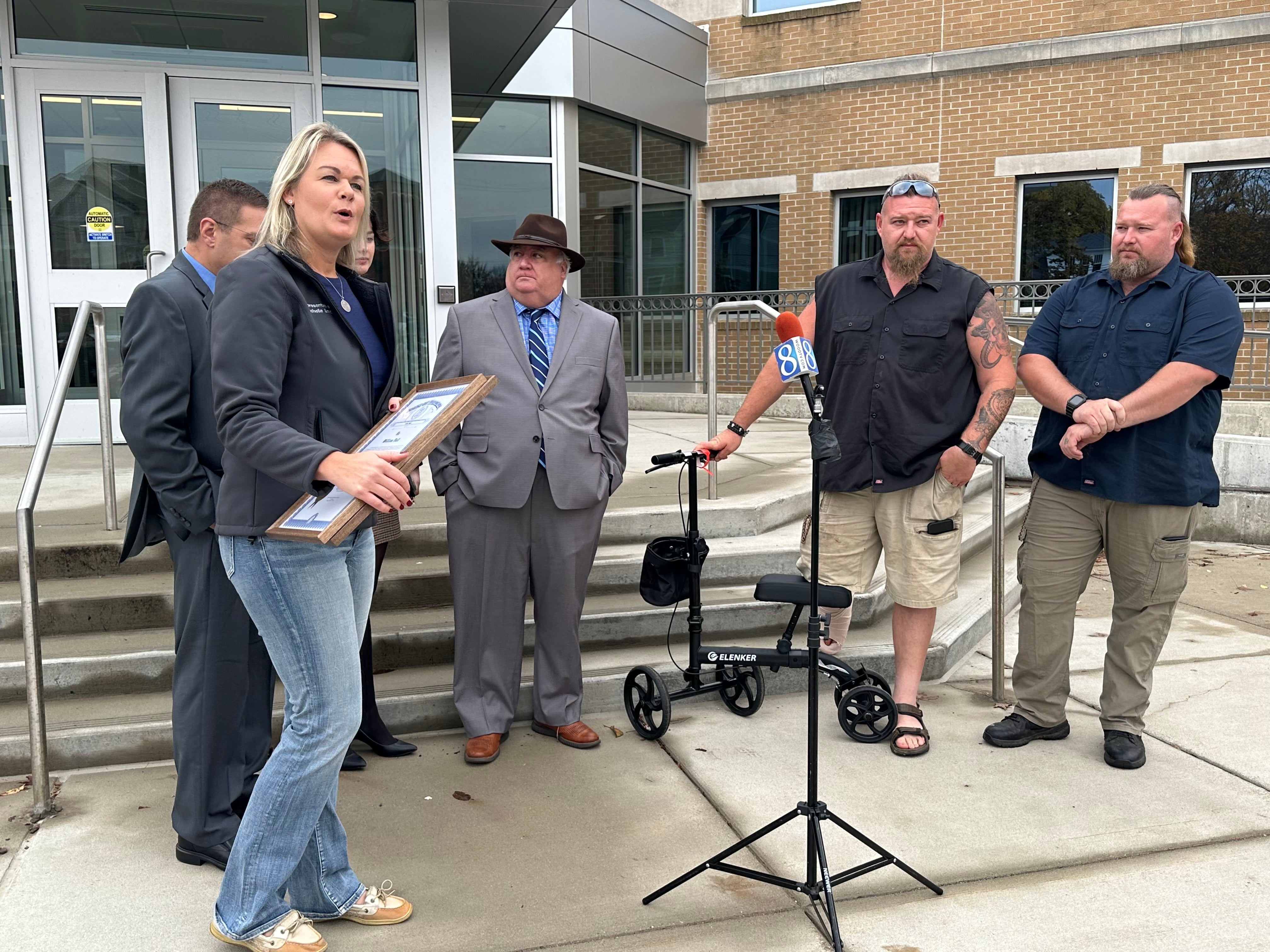 Michigan state rep Rachelle Smit, left, presents a plaque with Michigan state’s coat of arms to Michael and William Null on Friday 27 October