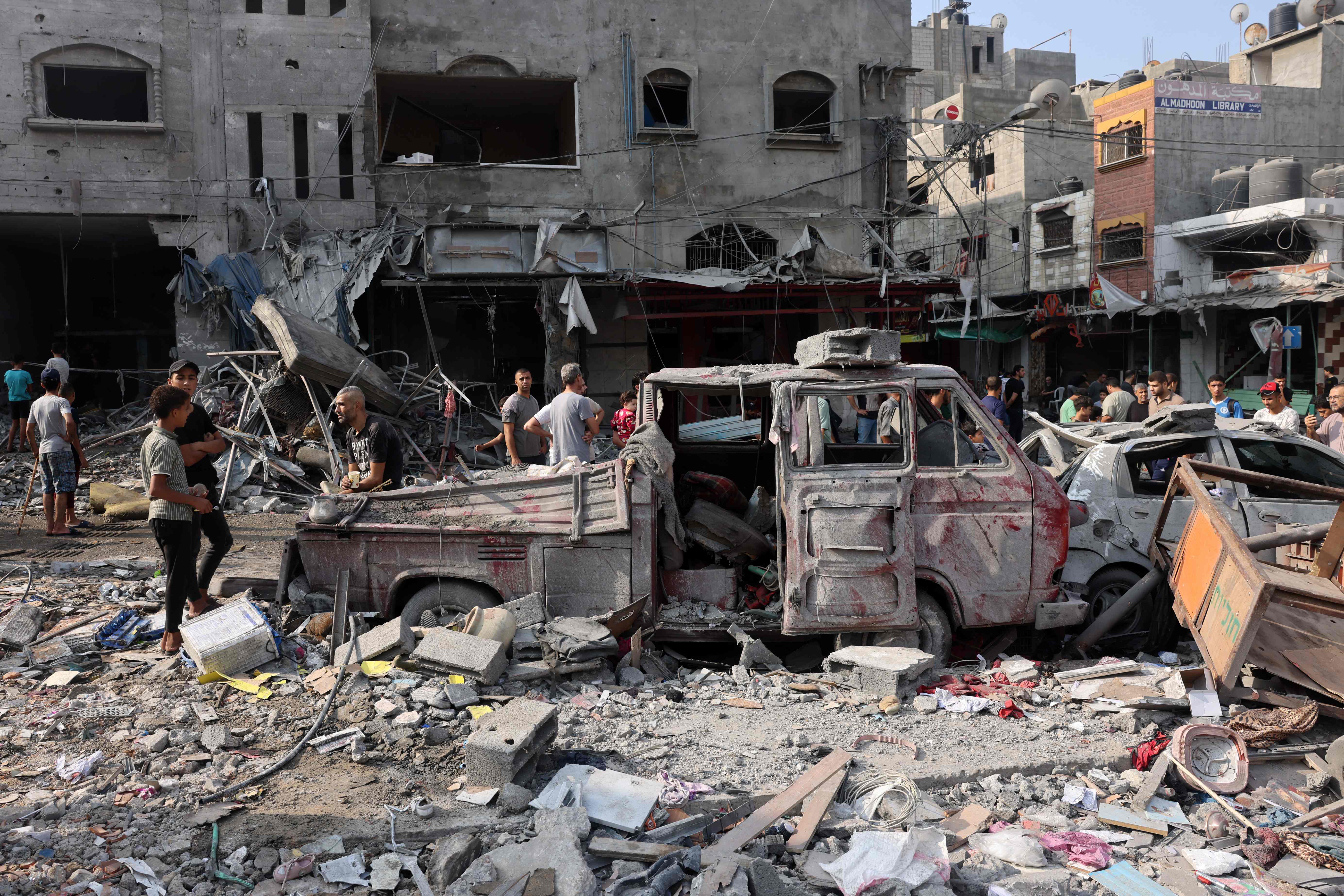 People gather amid the destruction following Israeli strikes on Al-Shatee camp in Gaza City