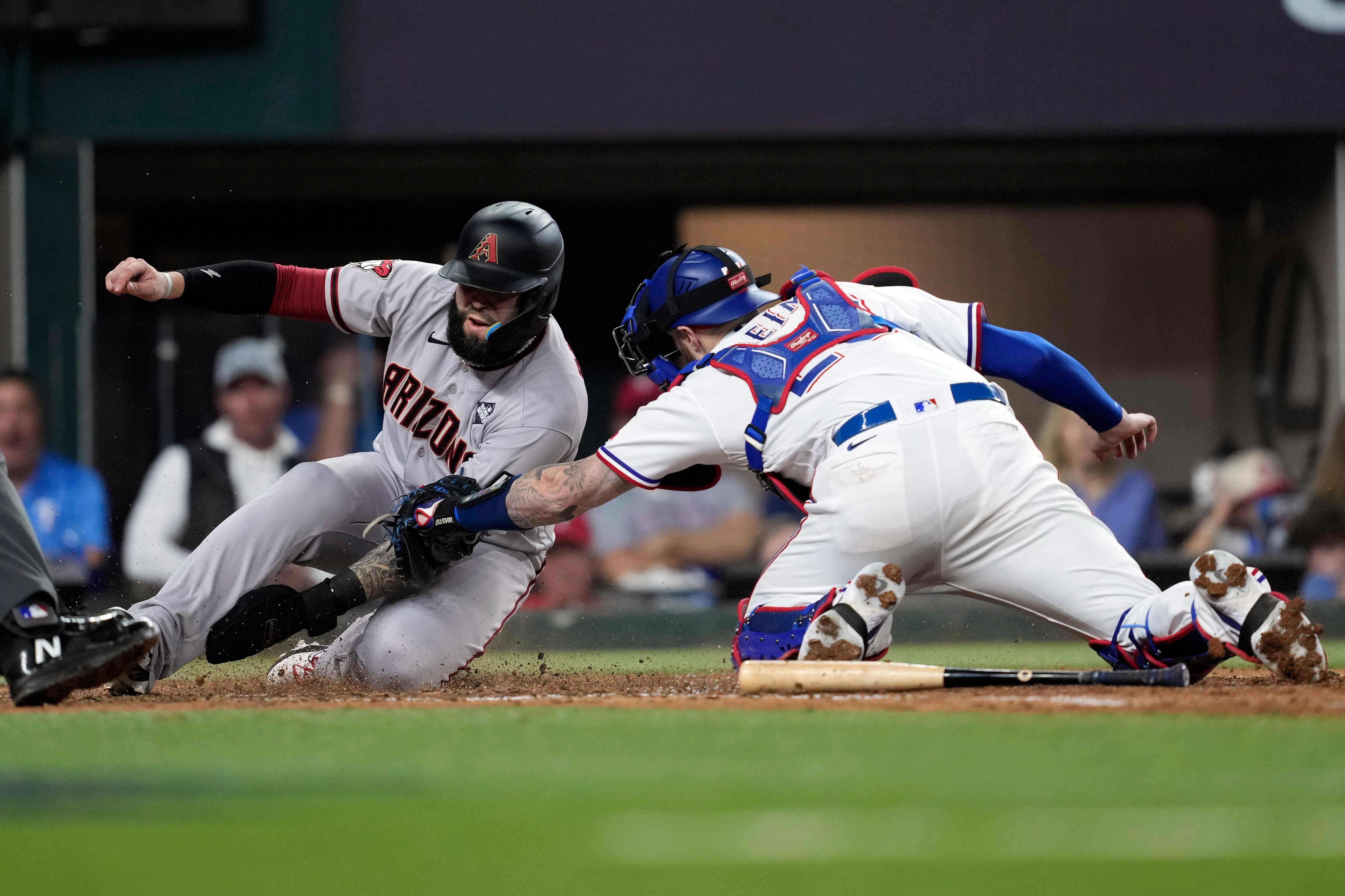 Arizona Diamondbacks’ Emmanuel Rivera, left, scores as Texas Rangers catcher Jonah Heim reaches to tag him during the eighth inning (Godofredo A Vasquez/AP)