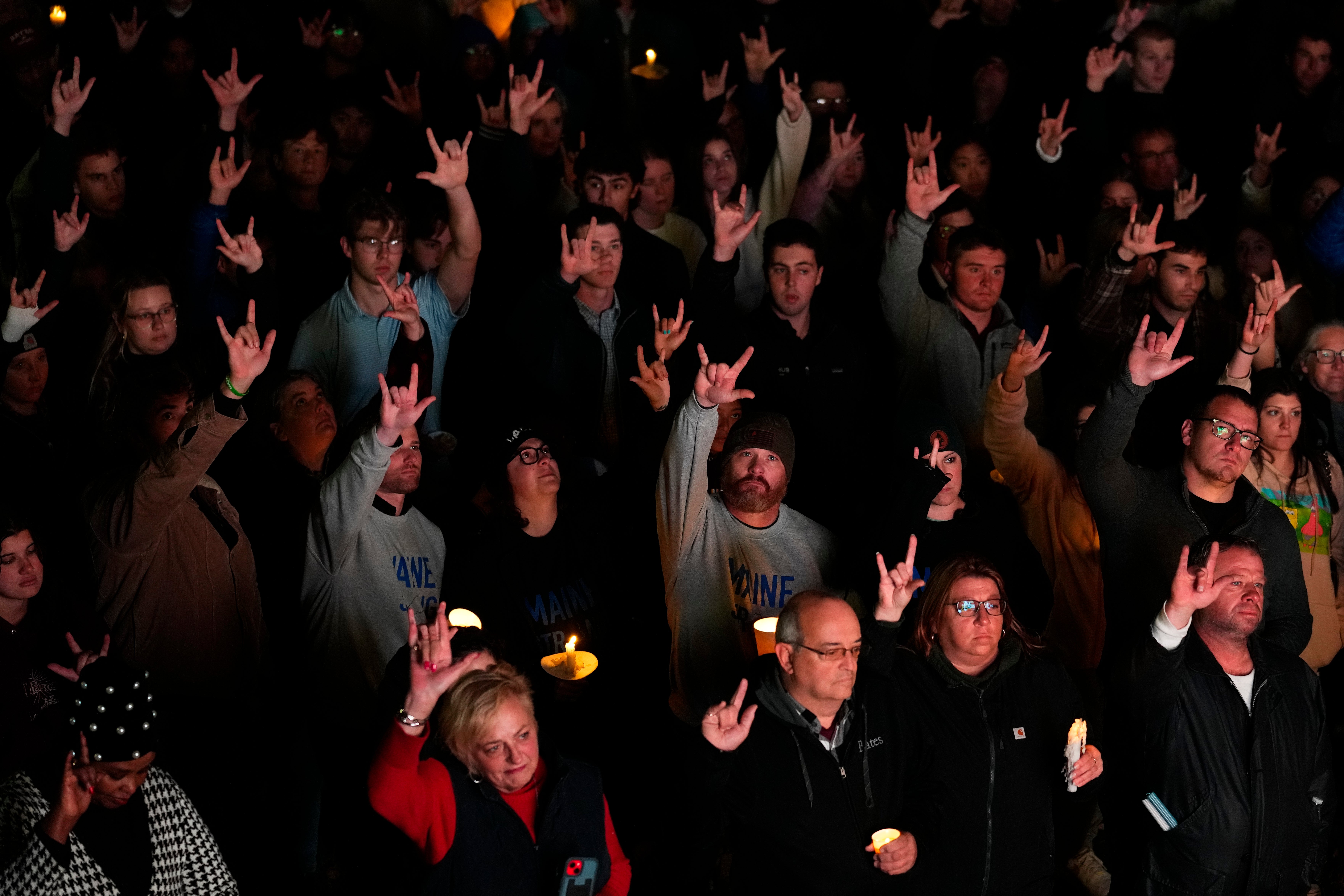 People sign "I love you" at a vigil for the victims of Wednesday's mass shootings, Sunday, Oct. 29, 2023, outside the Basilica of Saints Peter and Paul in Lewiston, Maine