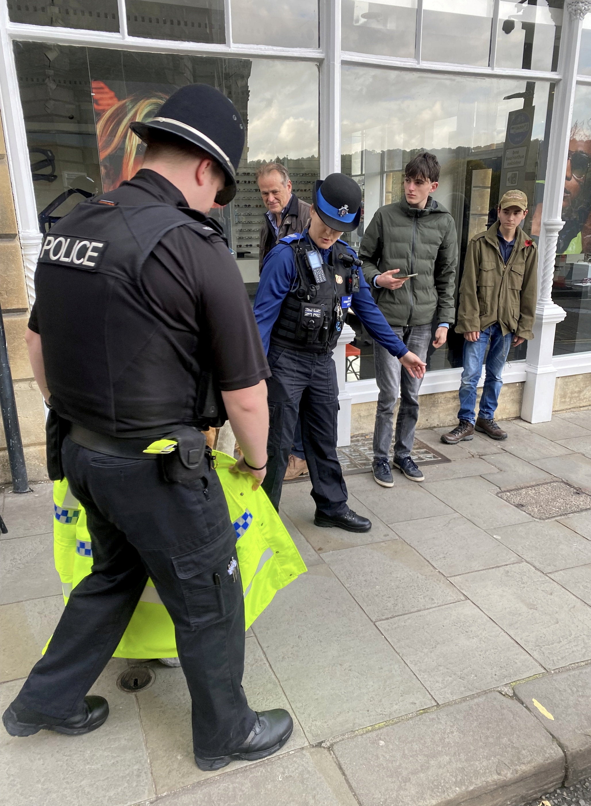 A police officer and two community support officers guide a lost swan back to the river near Pulteney bridge in Bath