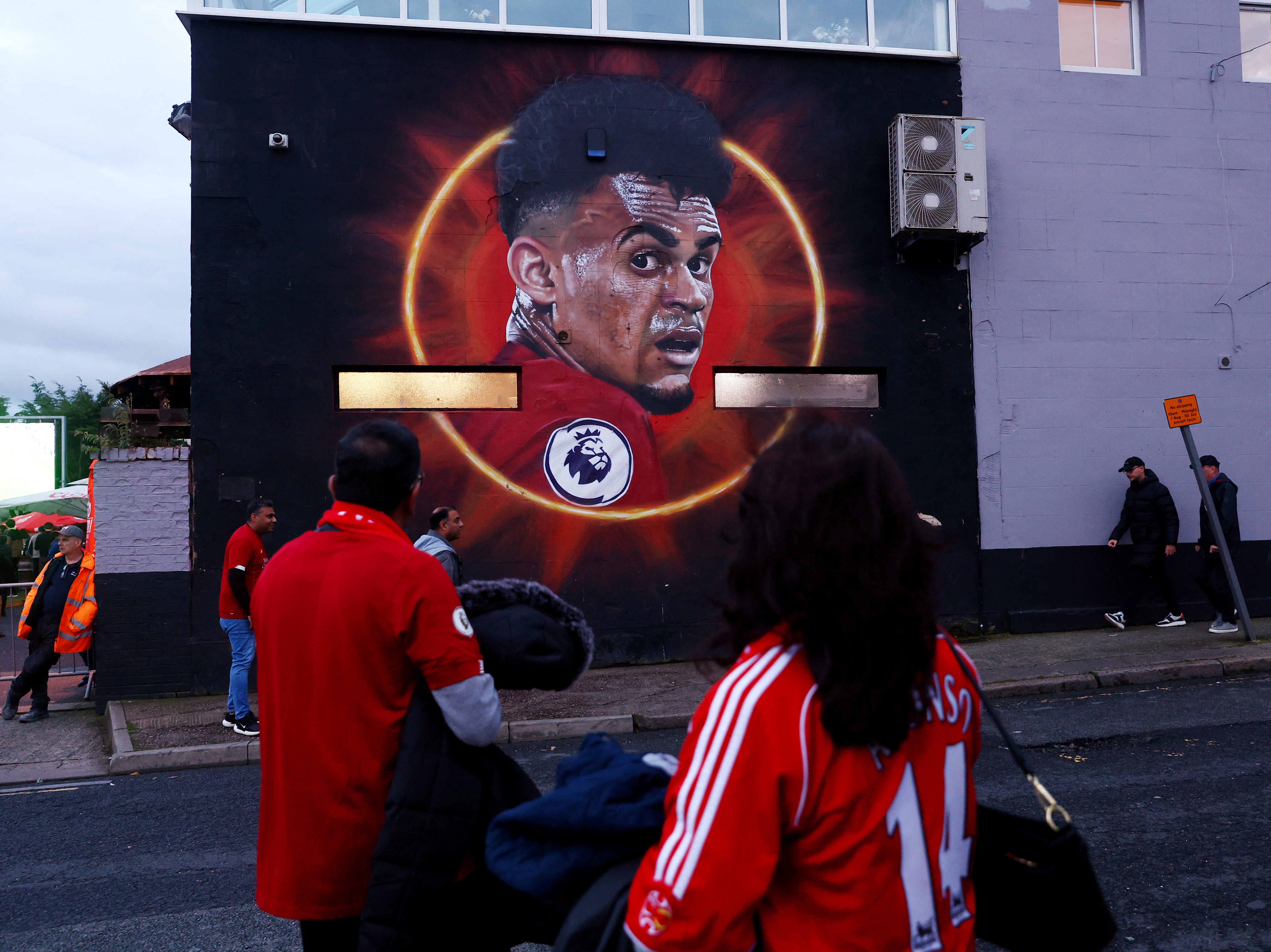 Liverpool fans walk past a mural of Diaz outside Anfield