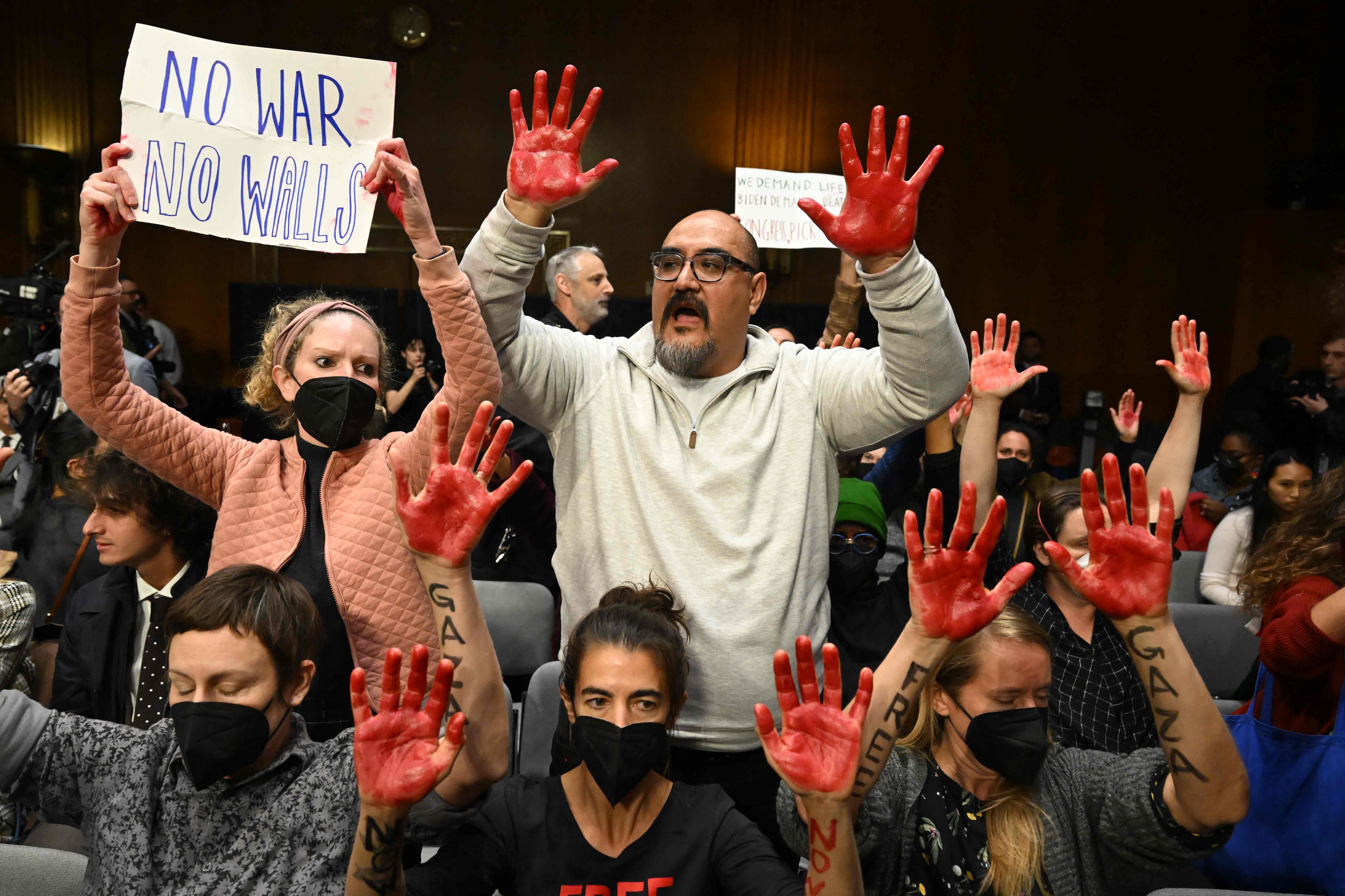 Protesters raise their painted hands as US Secretary of State Antony Blinken and Defense Secretary Lloyd Austin testify during a Senate Appropriations Committee hearing to examine the national security supplemental request