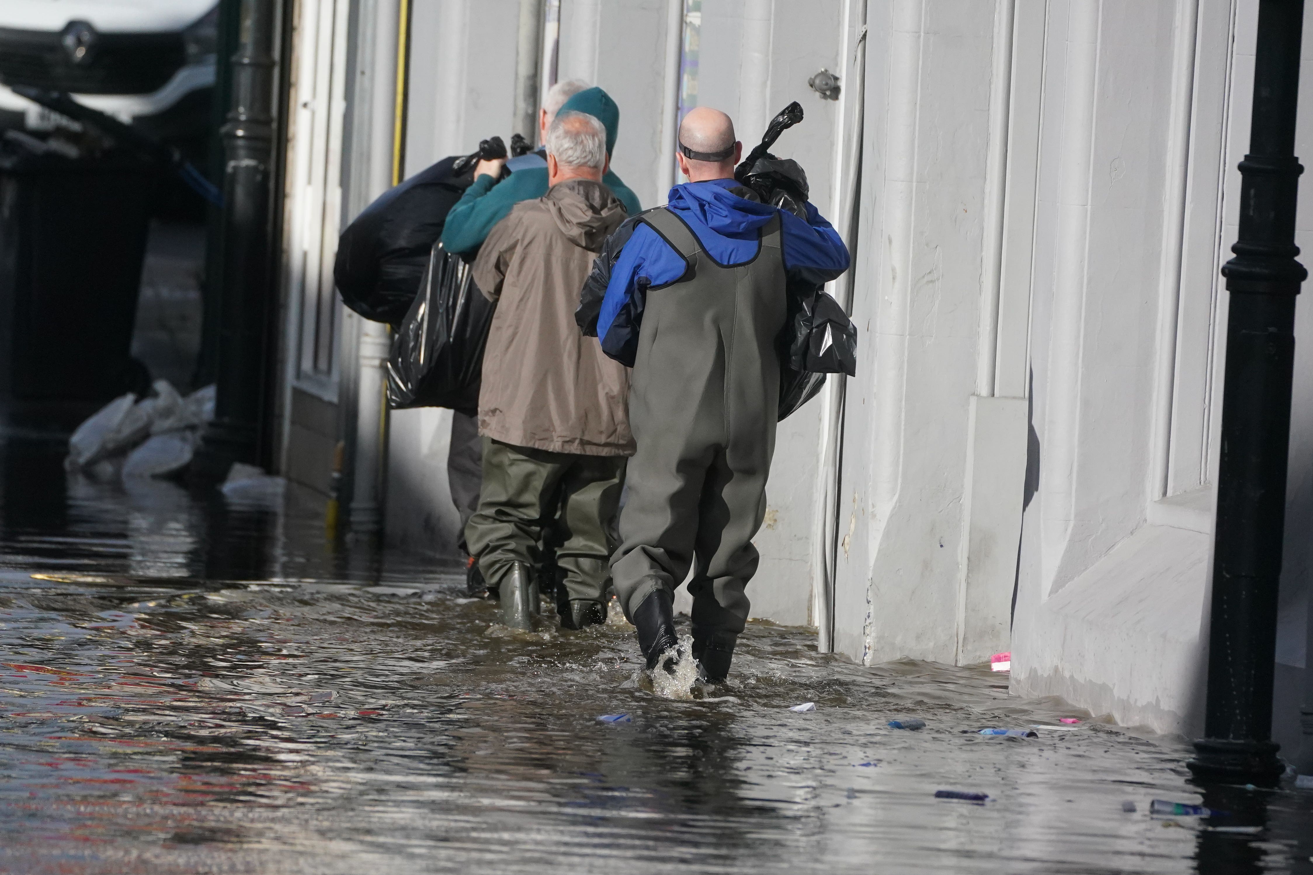 People clear out damaged shops in Sugar Island, Newry Town, Co Down, which has been swamped by floodwater as the city’s canal burst its banks amid heavy rainfall. Dozens of businesses were engulfed in the floods, with widespread damage caused to buildings, furnishings and stock (Brian Lawless/PA)