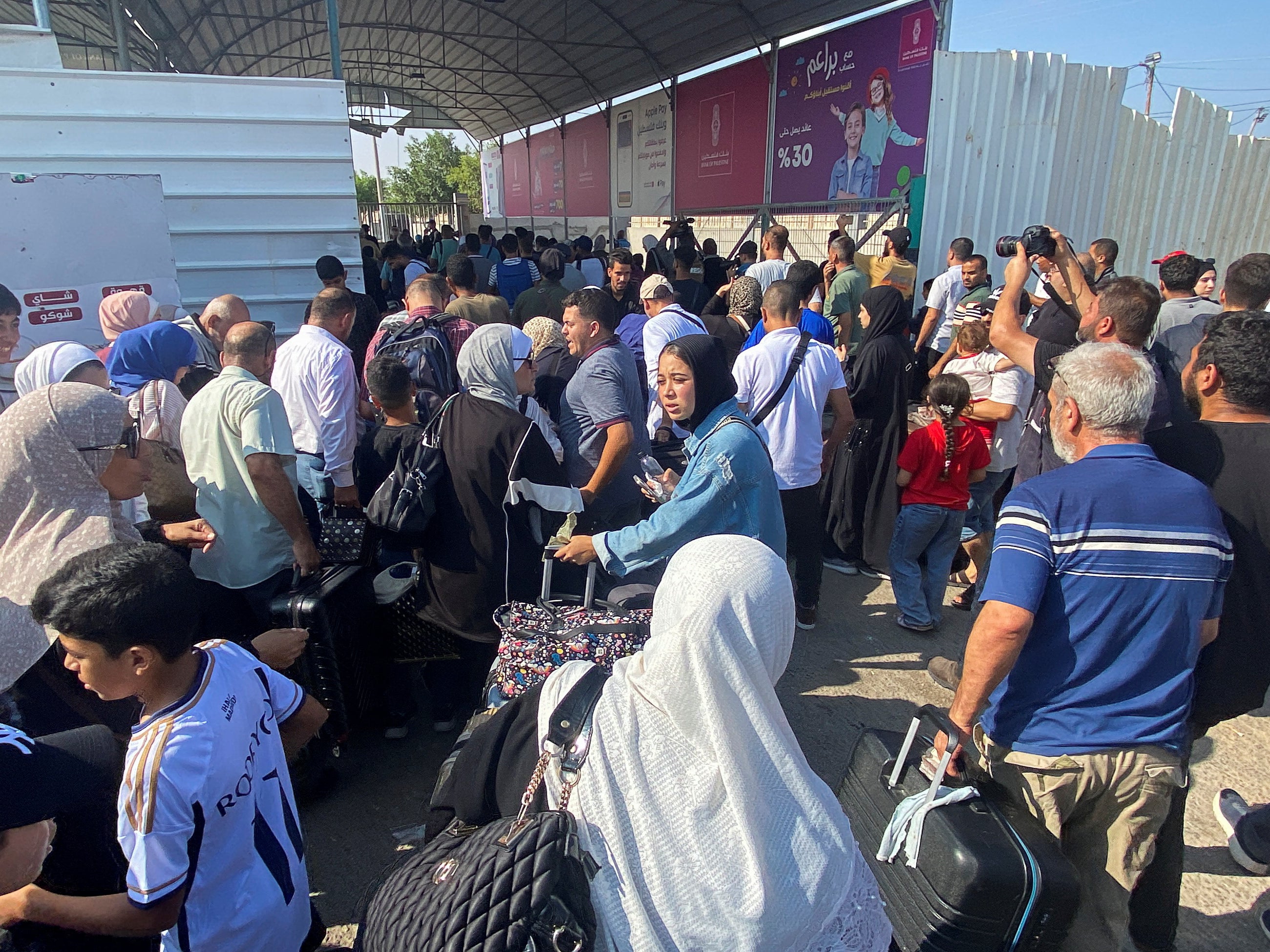 Palestinians with dual citizenship walk at the Rafah border crossing with Egypt in the hope they can leave