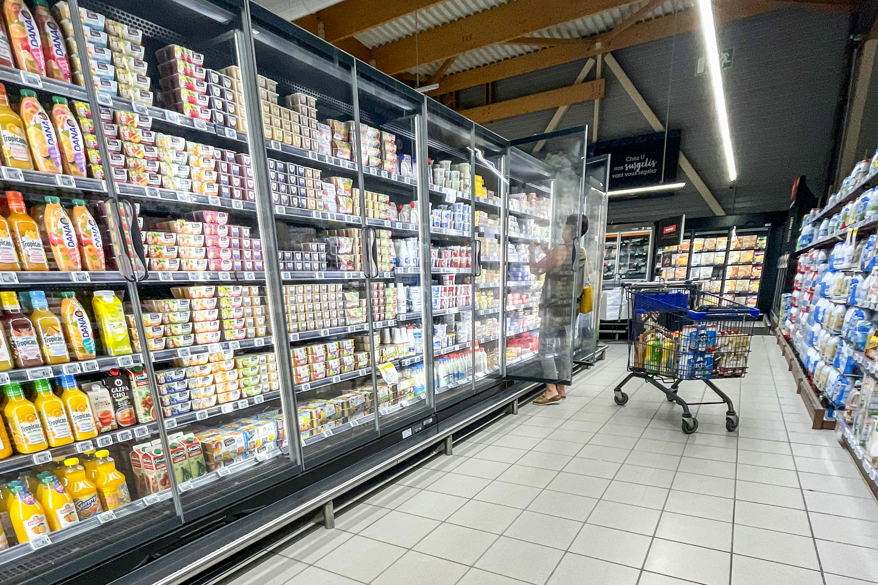 A customer grabs food from a fridge to fill her shopping cart in a supermarket near Lille, France