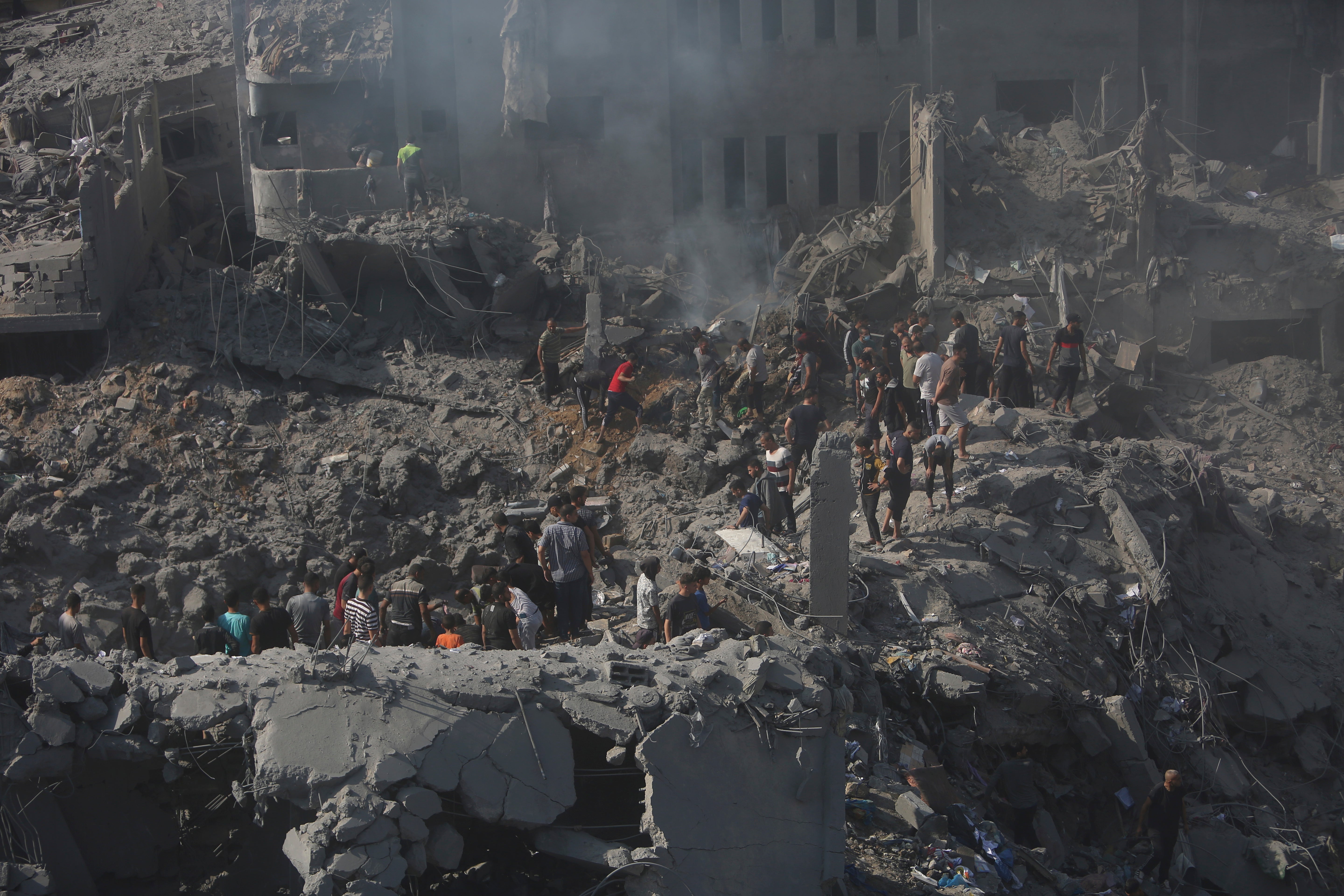 Palestinians look for survivors in the rubble of a building following an Israeli airstrike in Bureij refugee camp