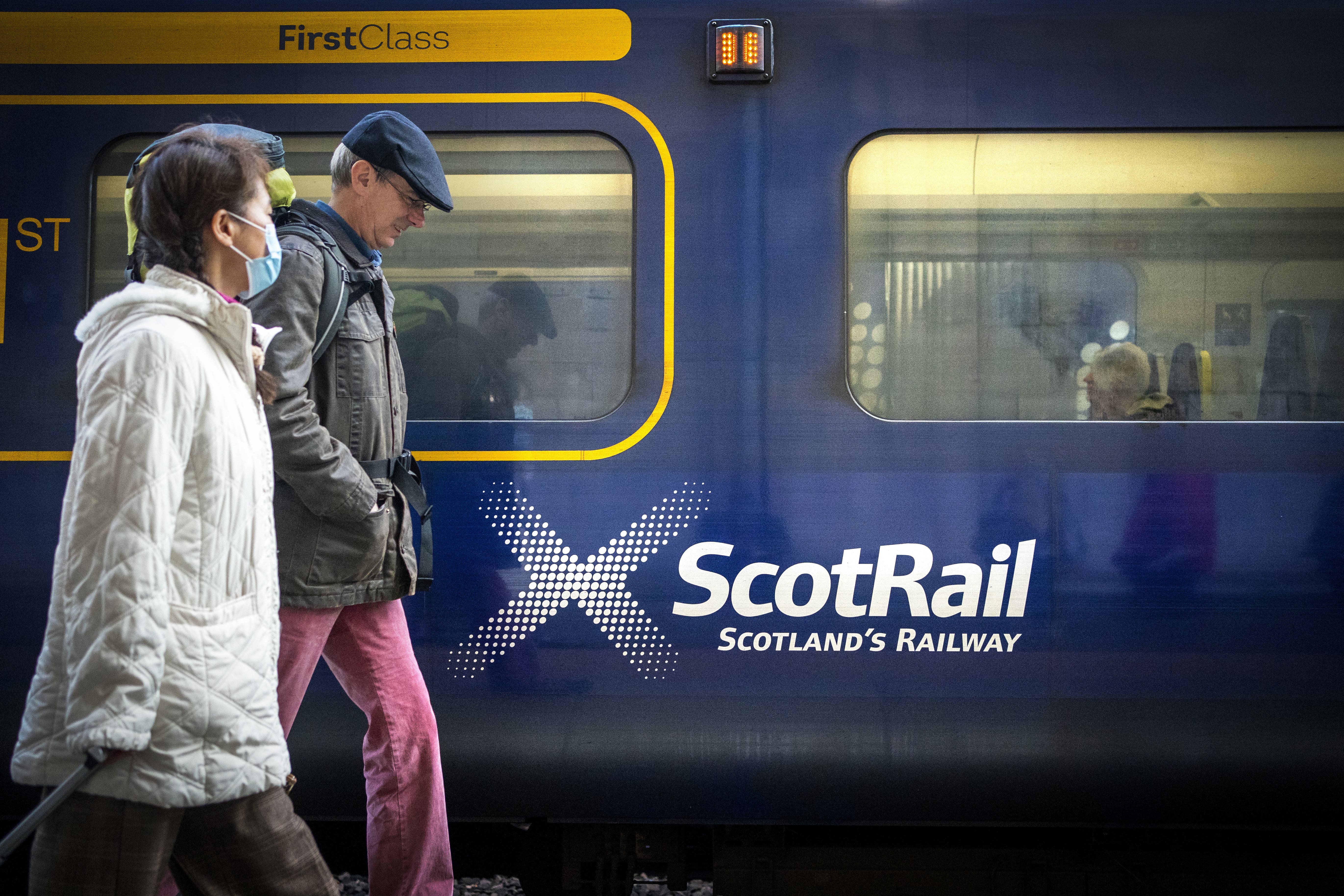 Commuters walking past a ScotRail train (Jane Barlow/PA)