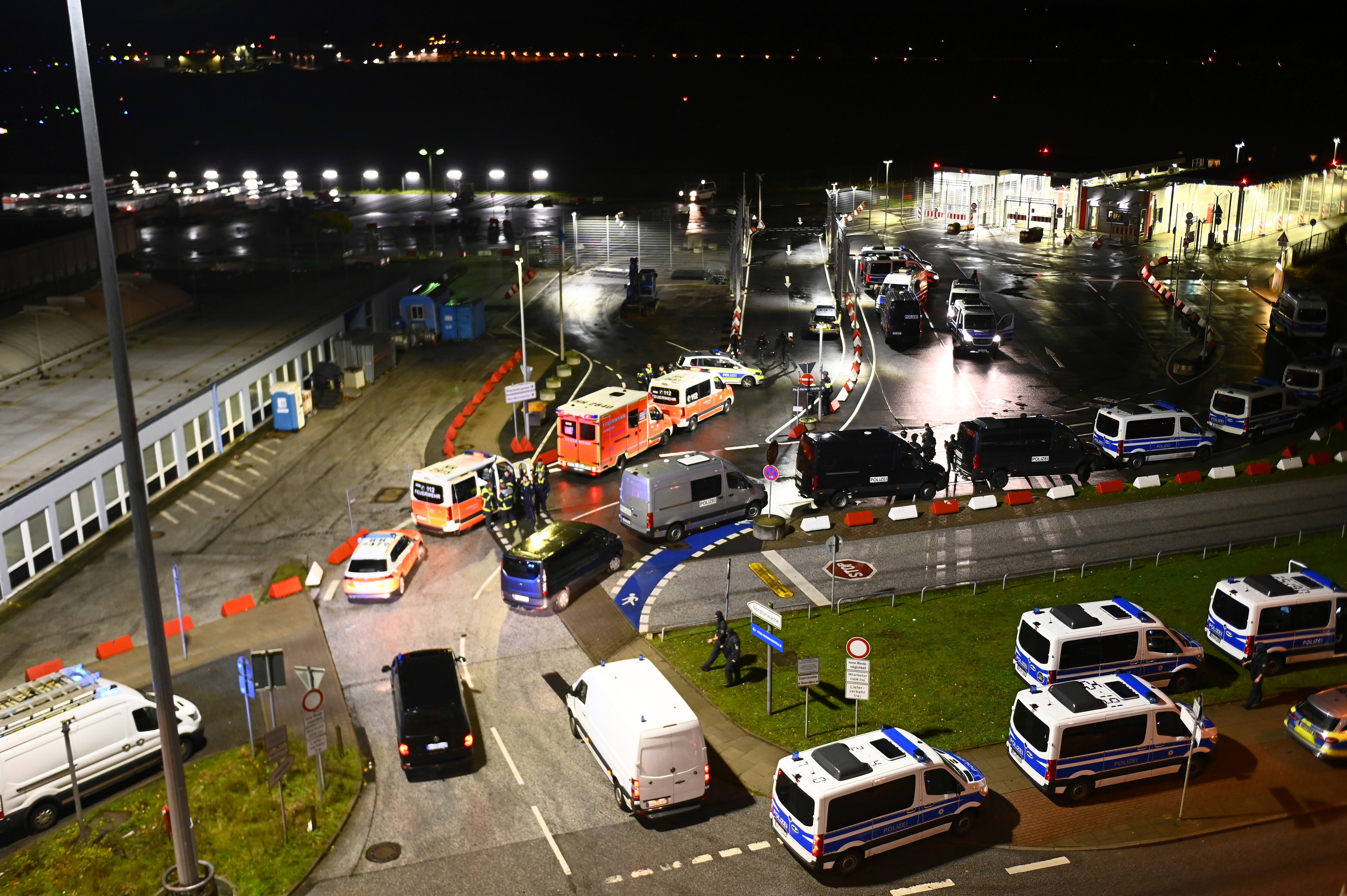 Police vehicles and ambulances arrive at Hamburg airport after an armed man drove through a gate