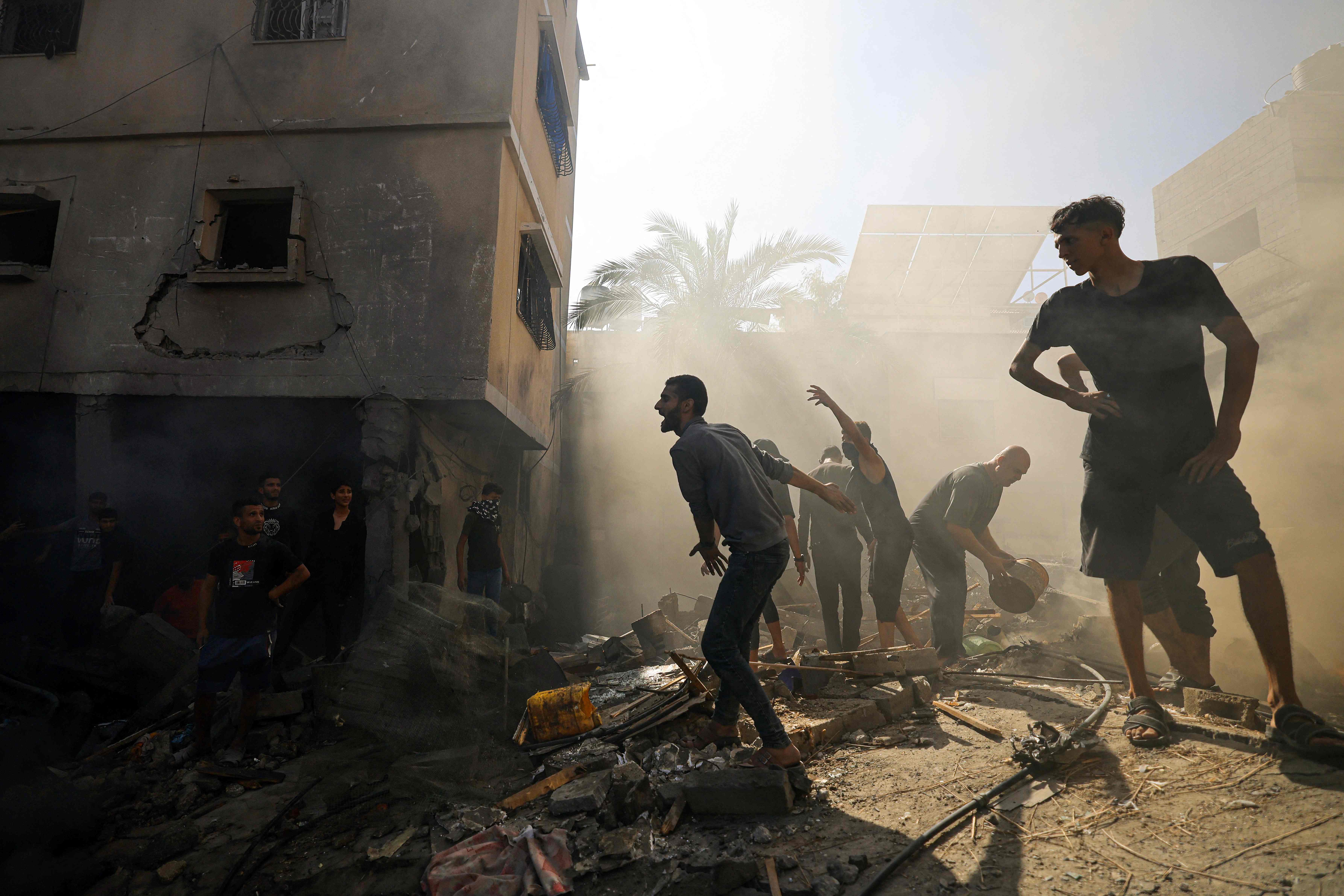 Palestinians stand amid rubble of a building in Khan Yunis, southern Gaza, amid ongoing Israeli airstrikes on the region